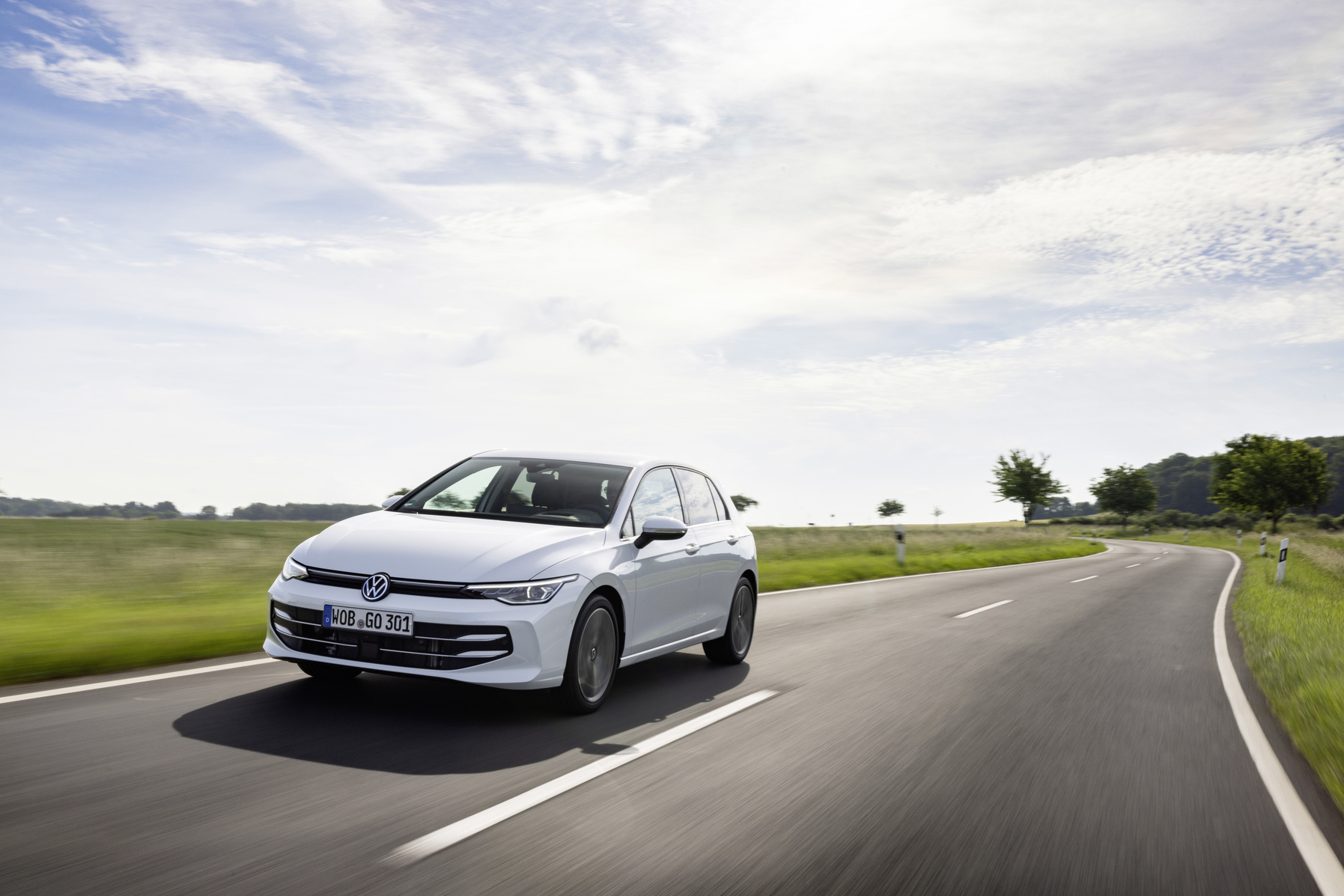 Ein weißer VW Golf fährt eine Landstraße entlang.