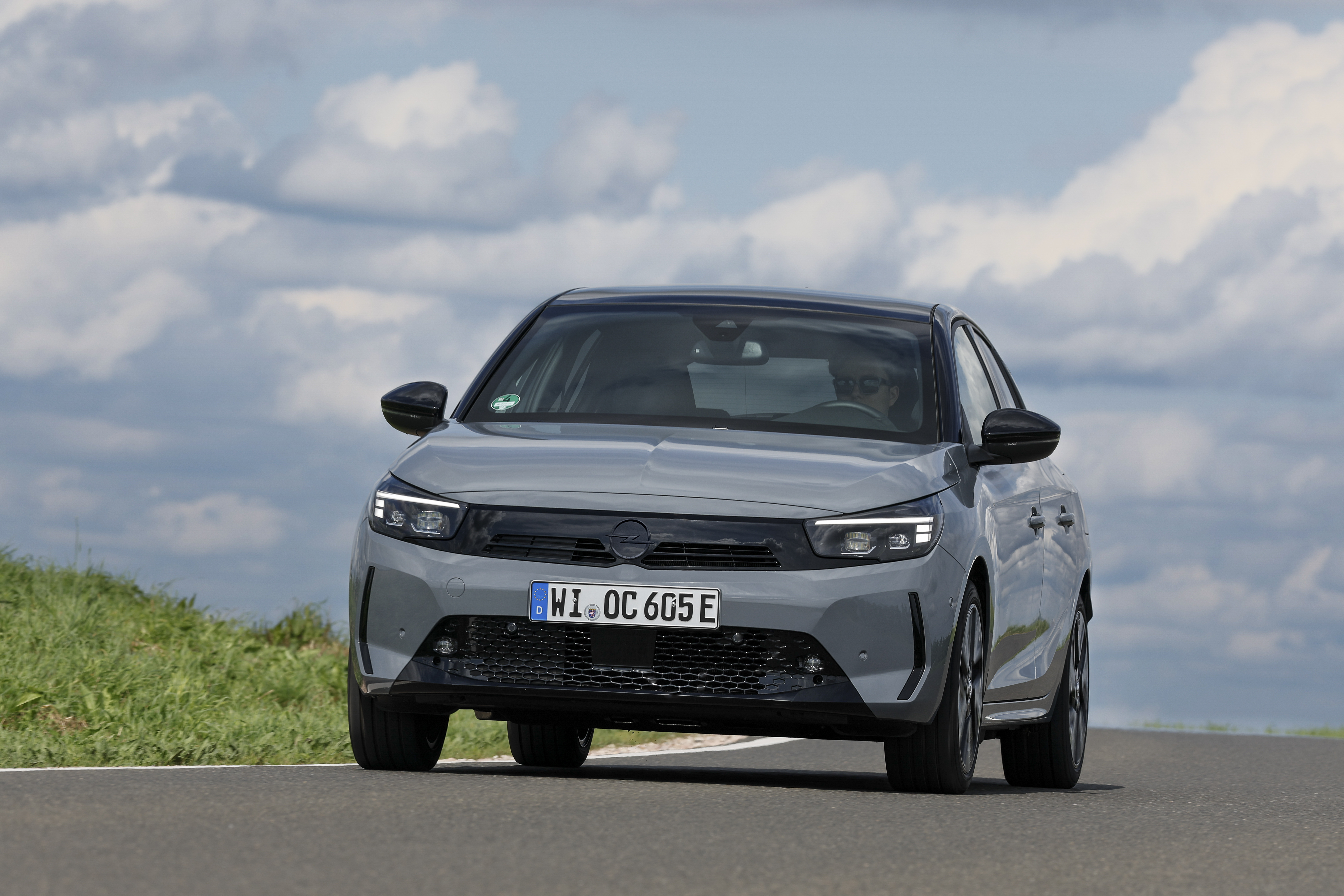 Ein grauer Opel Corsa Electric fährt eine Landstraße entlang.