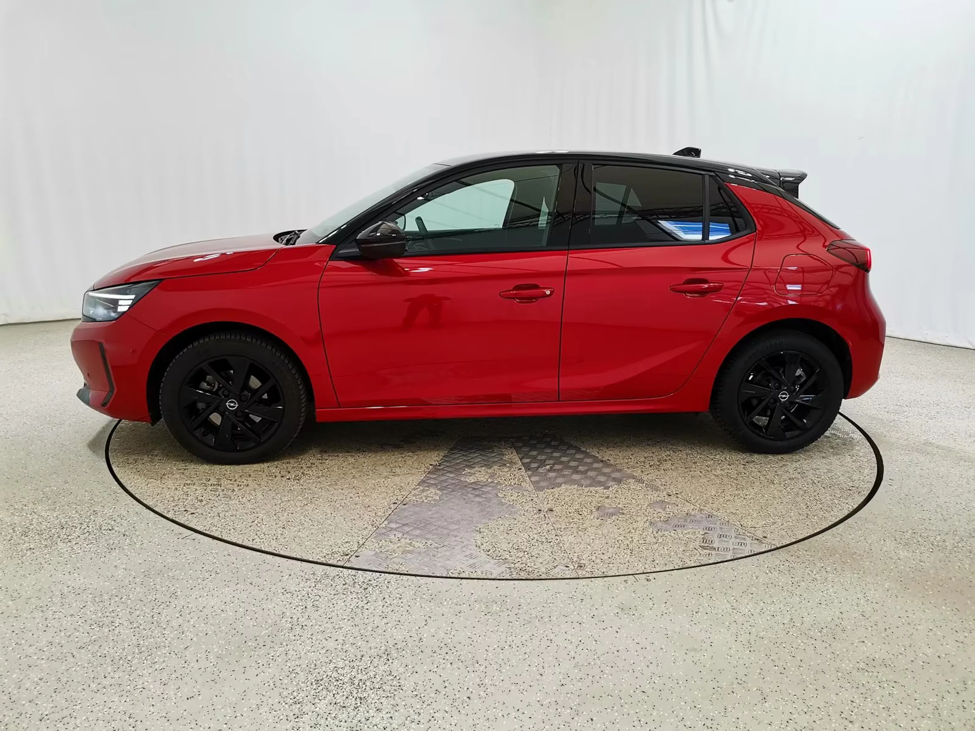 Ein roter Opel Corsa steht auf einer Verkaufsfläche.