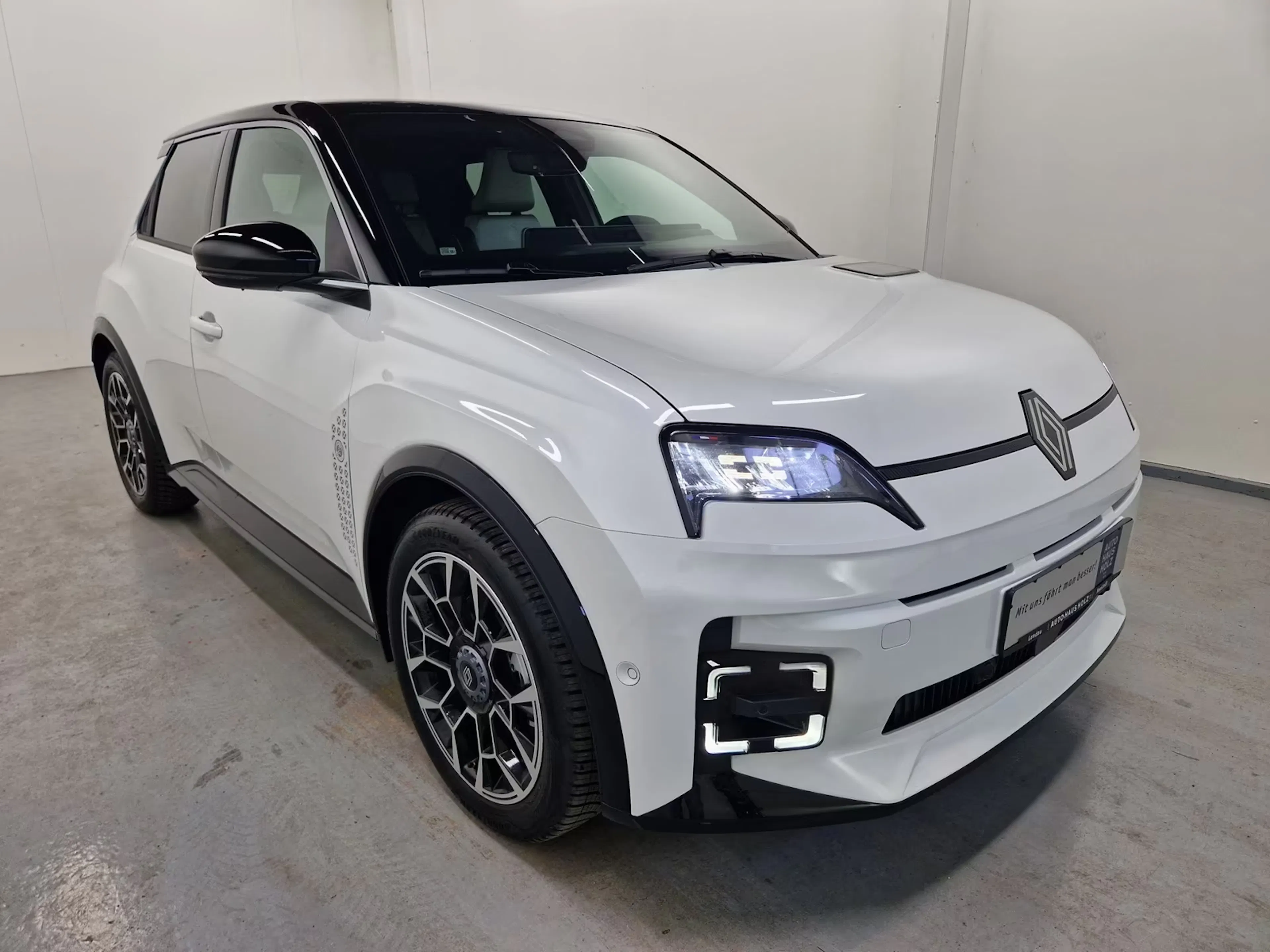 Ein weißer Renault 5 E-Tech steht im Verkaufsraum.