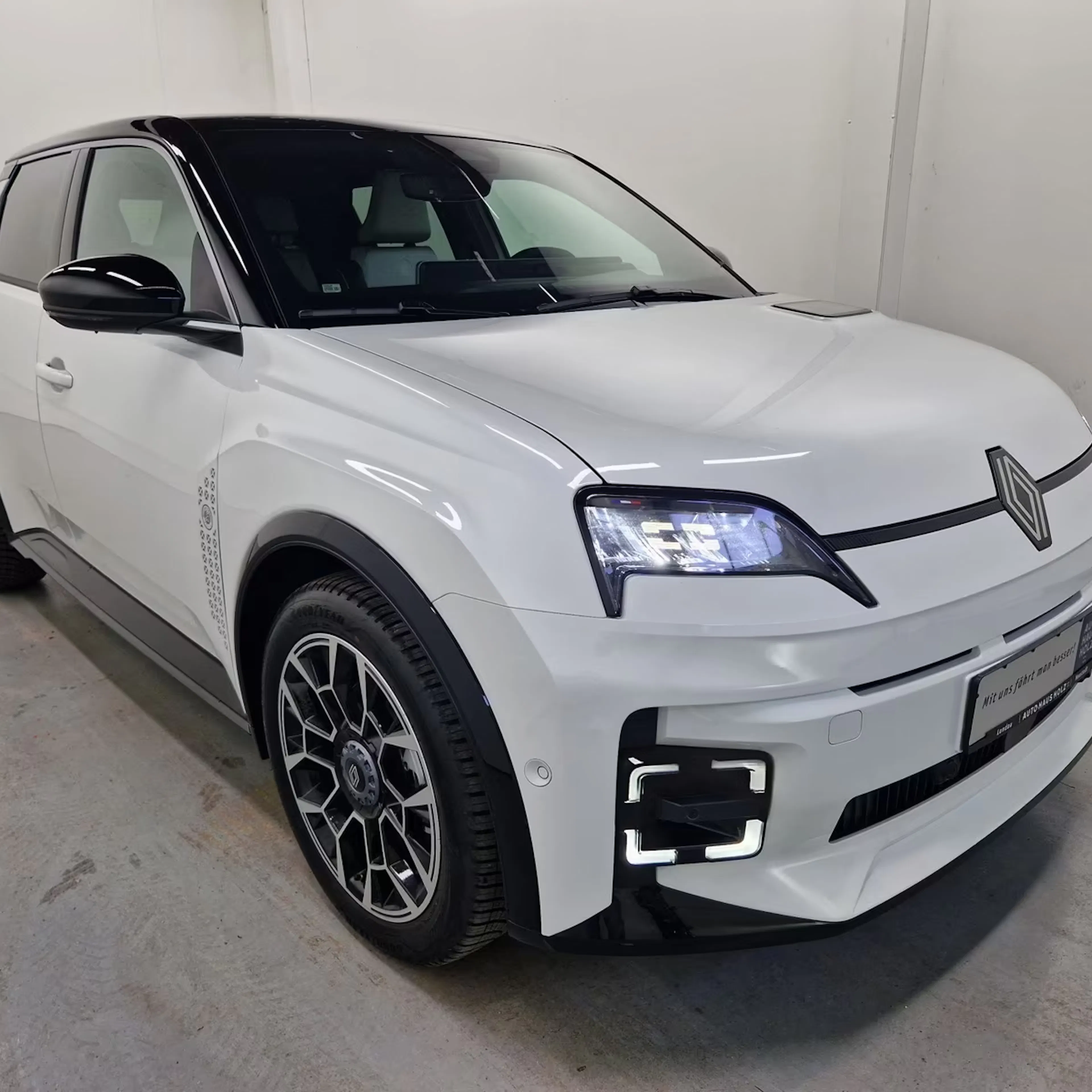 Ein weißer Renault 5 E-Tech steht im Verkaufsraum.