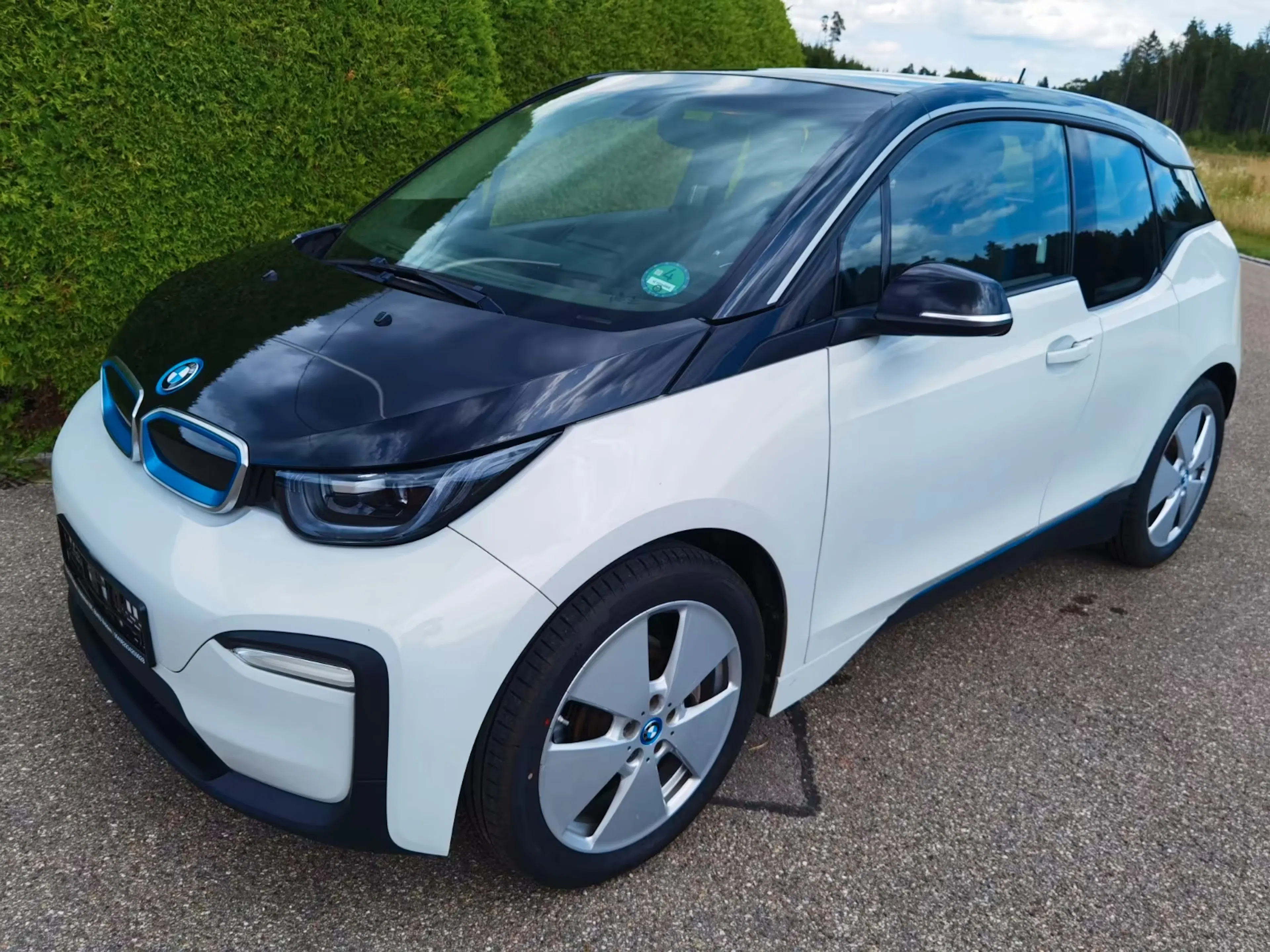 Ein weißer BMW i3 steht auf einr gepflasterten Fläche.