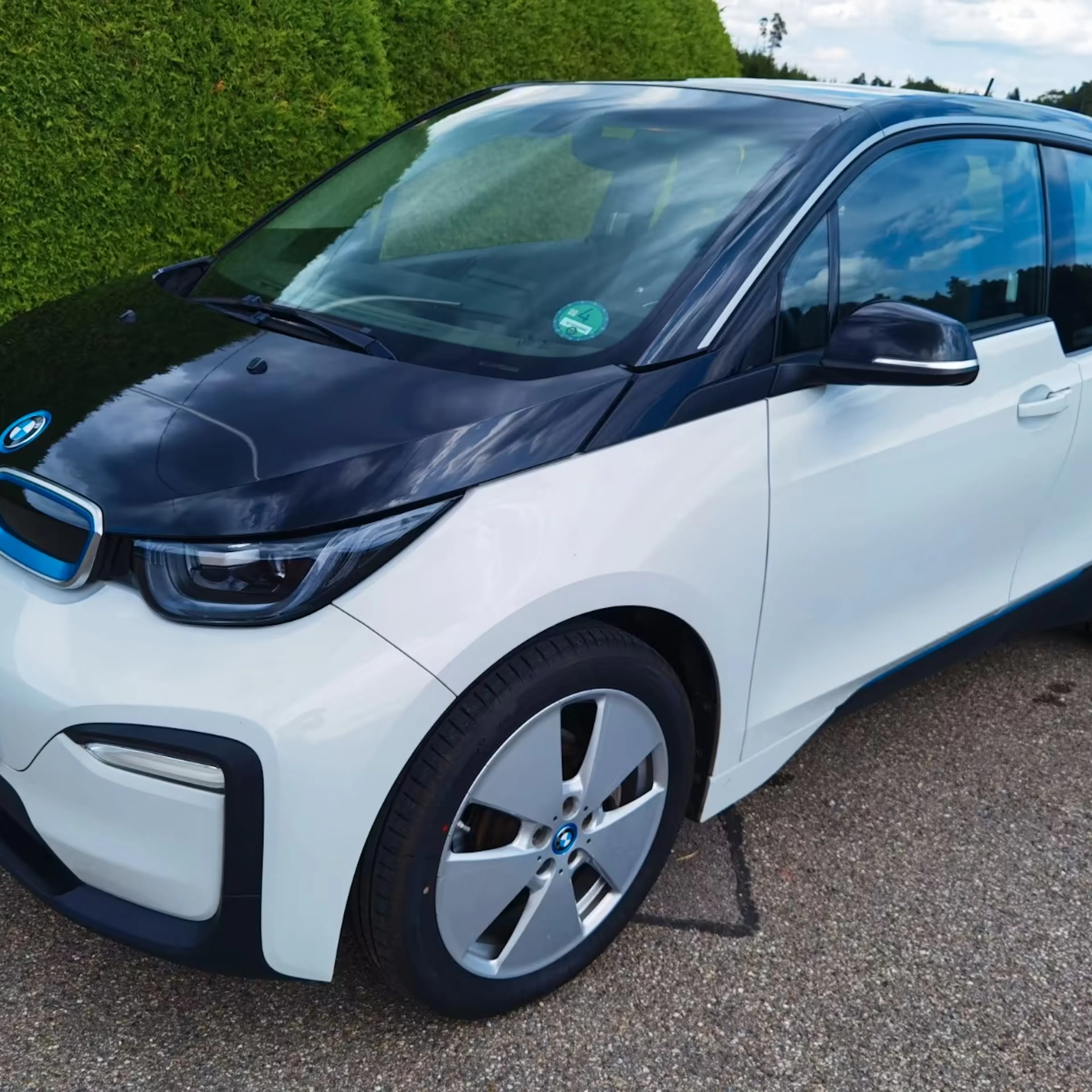 Ein weißer BMW i3 steht auf einr gepflasterten Fläche.