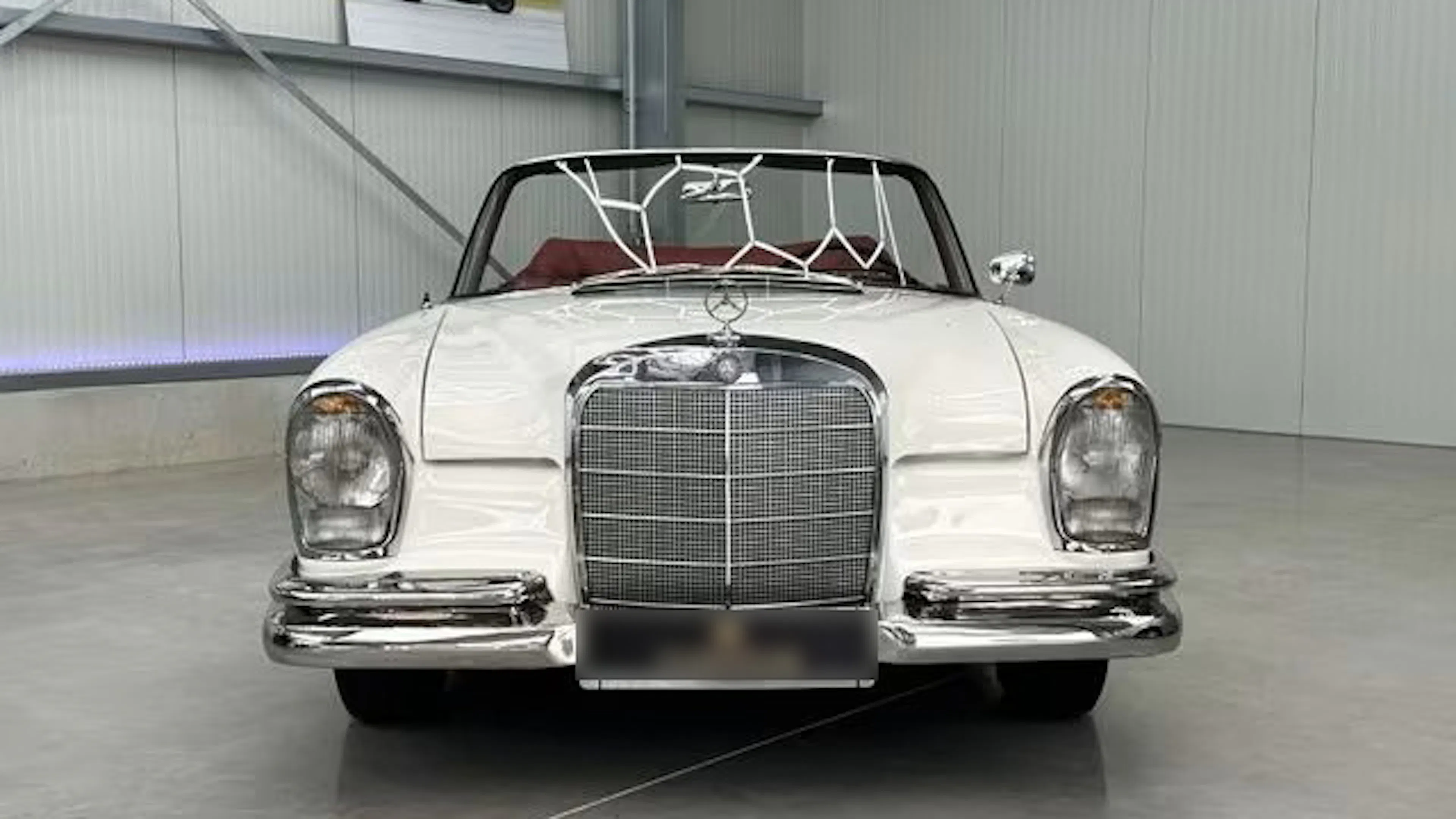Ein weißer Mercedes-Benz 300, der früher dem Schauspieler James Mason gehörte, steht in einer Garage.
