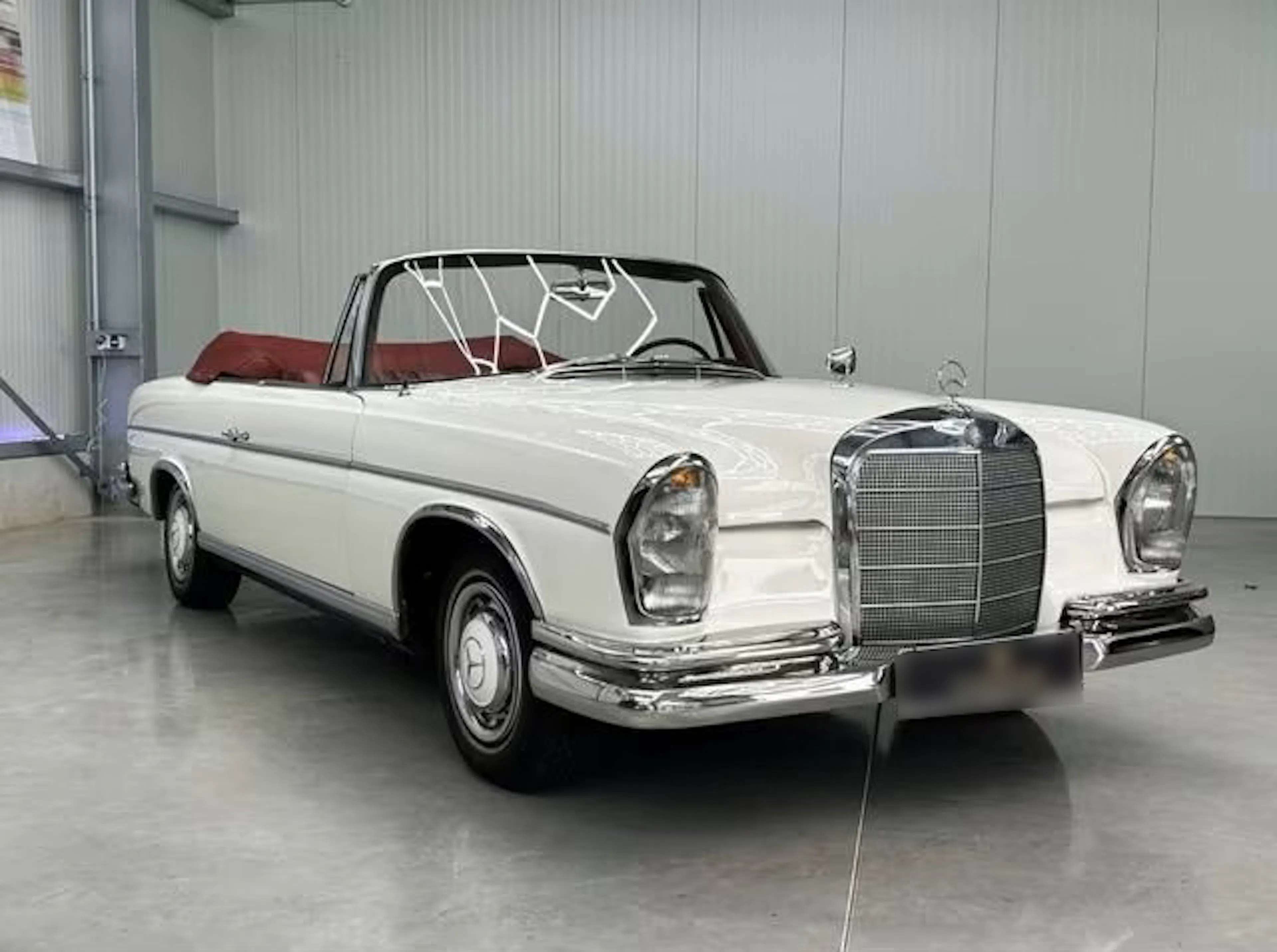 Ein weißer Mercedes-Benz 300, der früher dem Schauspieler James Mason gehörte, steht in einer Garage.