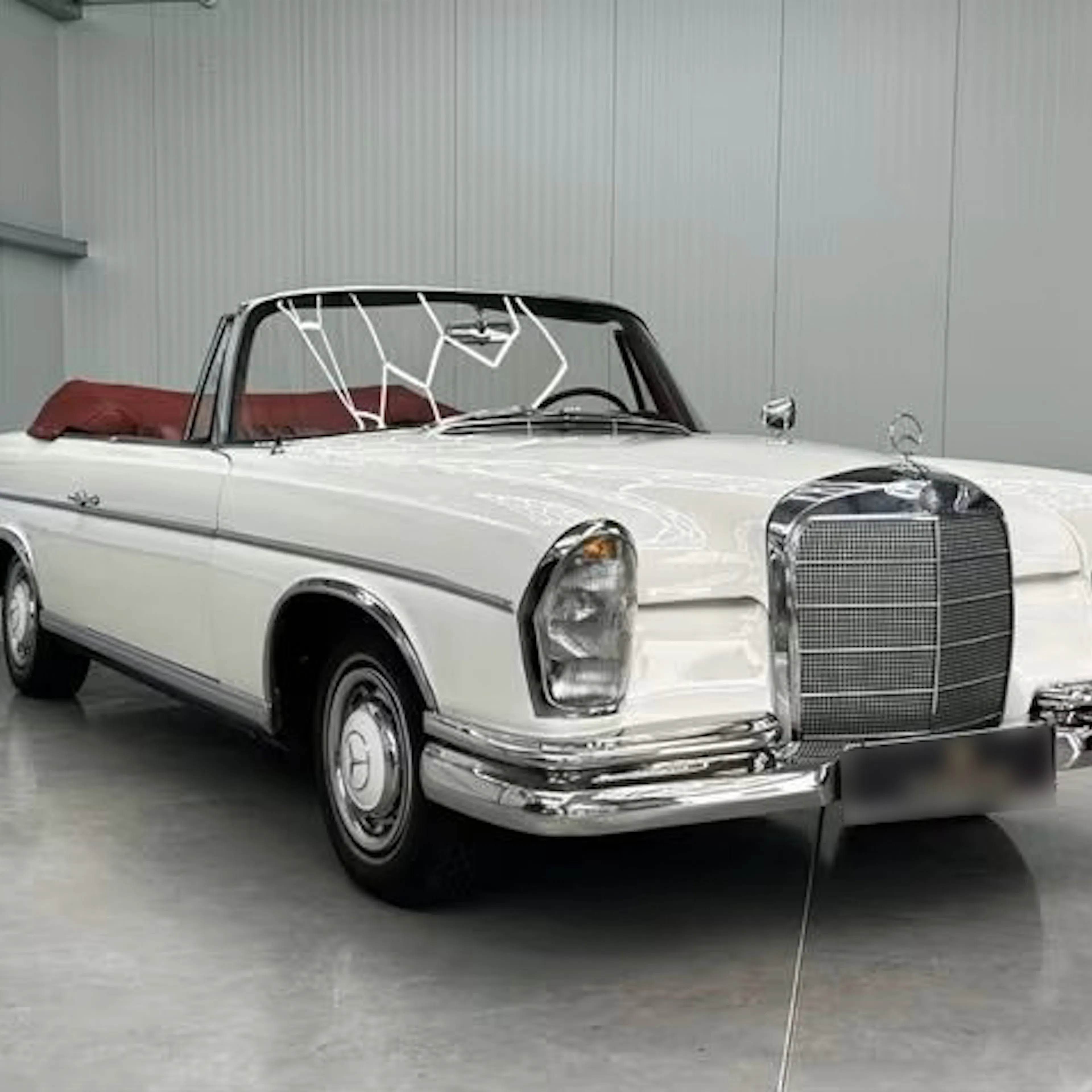 Ein weißer Mercedes-Benz 300, der früher dem Schauspieler James Mason gehörte, steht in einer Garage.