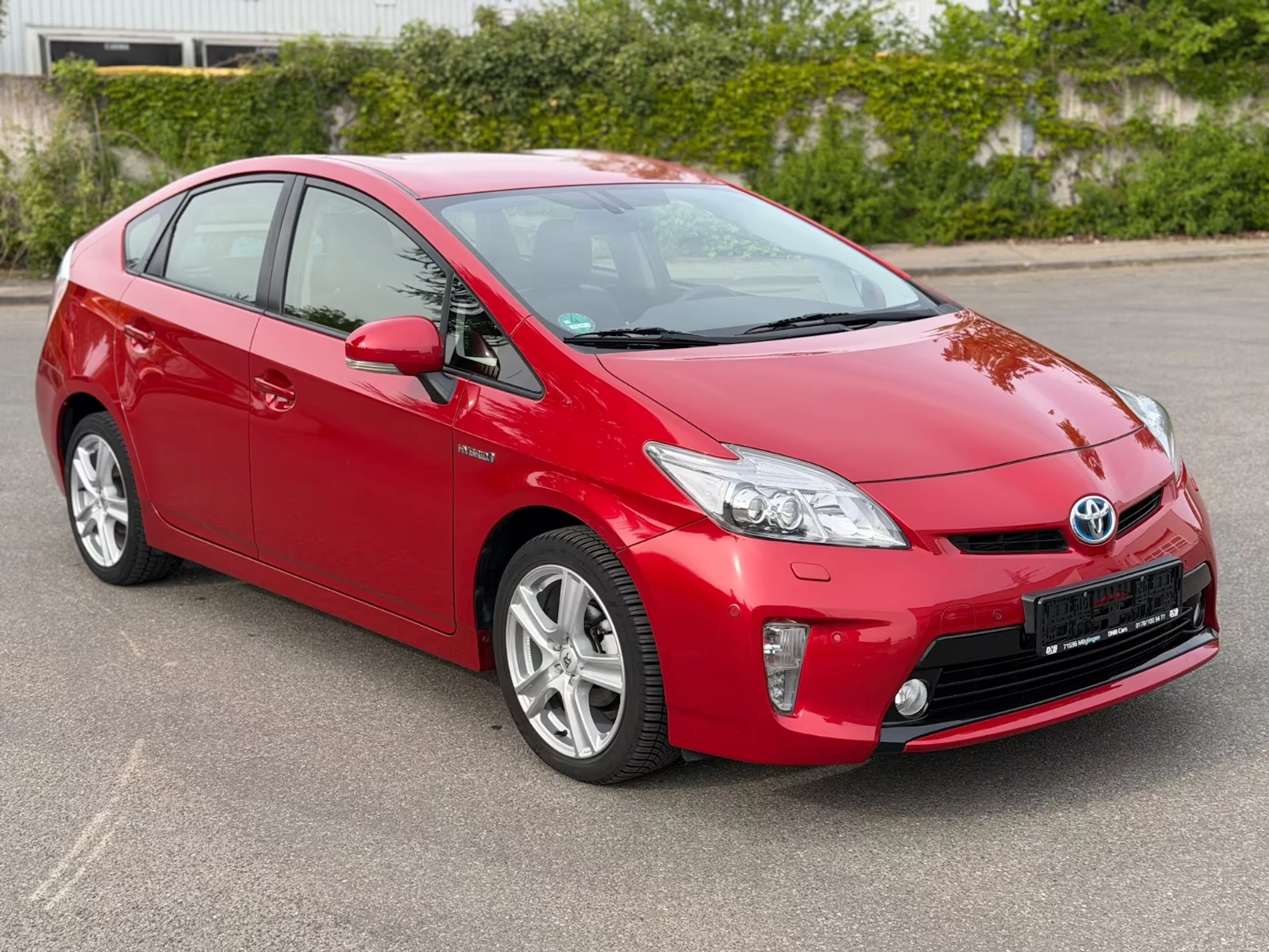 Ein roter Toyota Prius steht auf der Straße.
