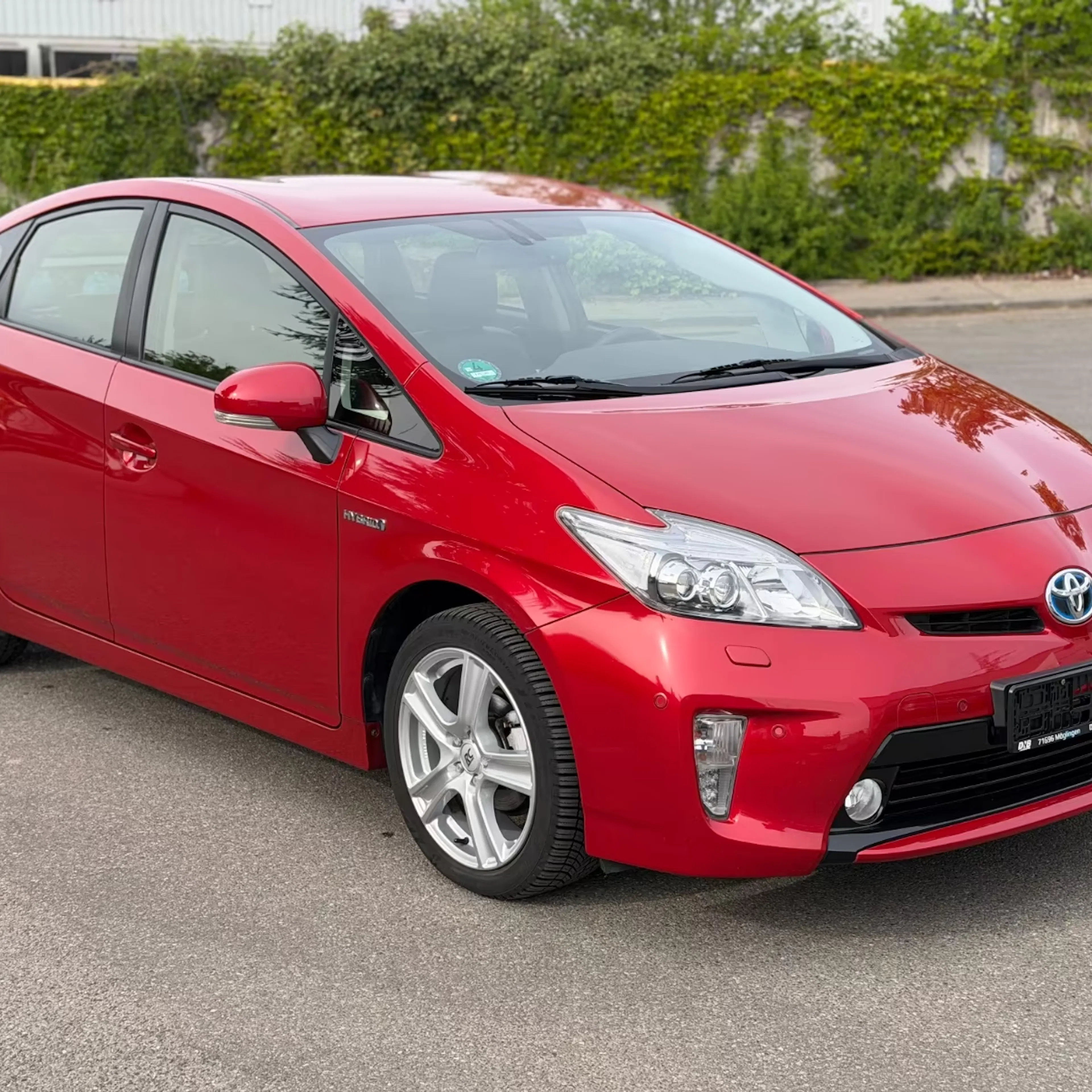 Ein roter Toyota Prius steht auf der Straße.