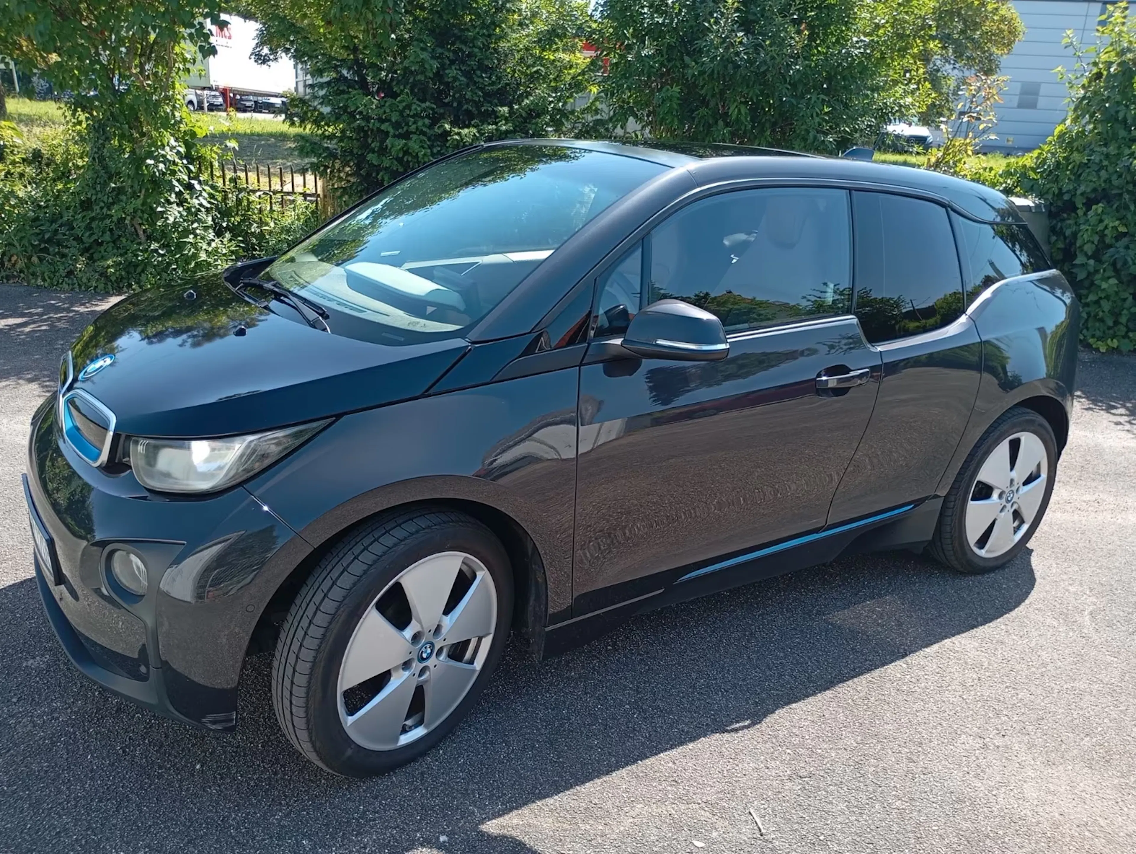 Ein grauer BMW i3 steht auf einer gepflasterten Fläche.