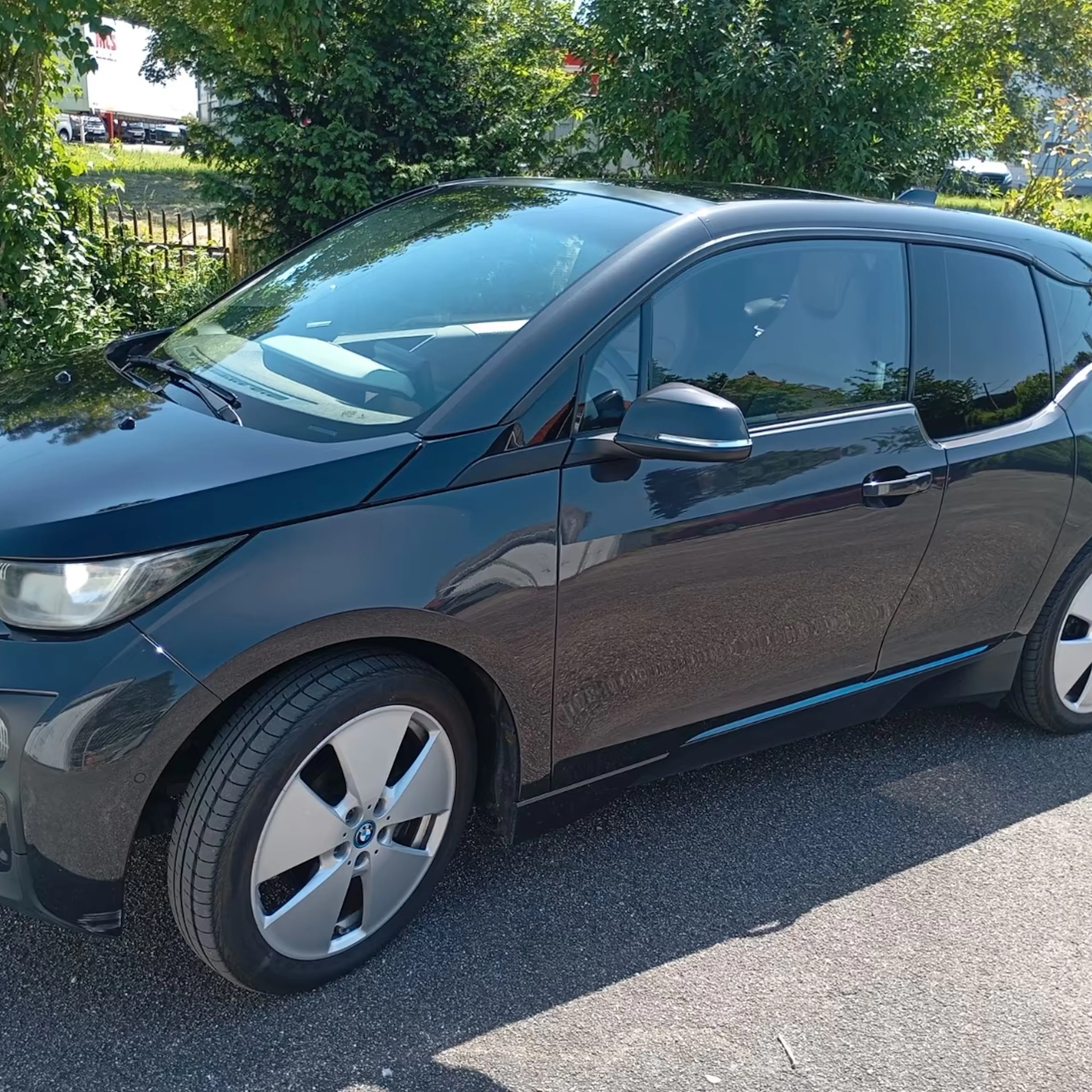 Ein grauer BMW i3 steht auf einer gepflasterten Fläche.
