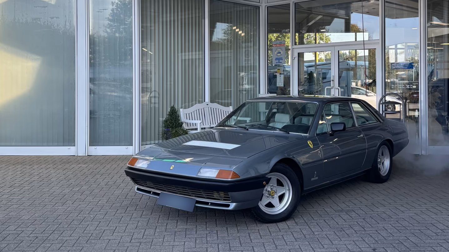 Der Ferrari 400 i V12, der einst dem Formel-1-Weltmeister Jody Scheckter gehörte, steht vor einem Autohaus.