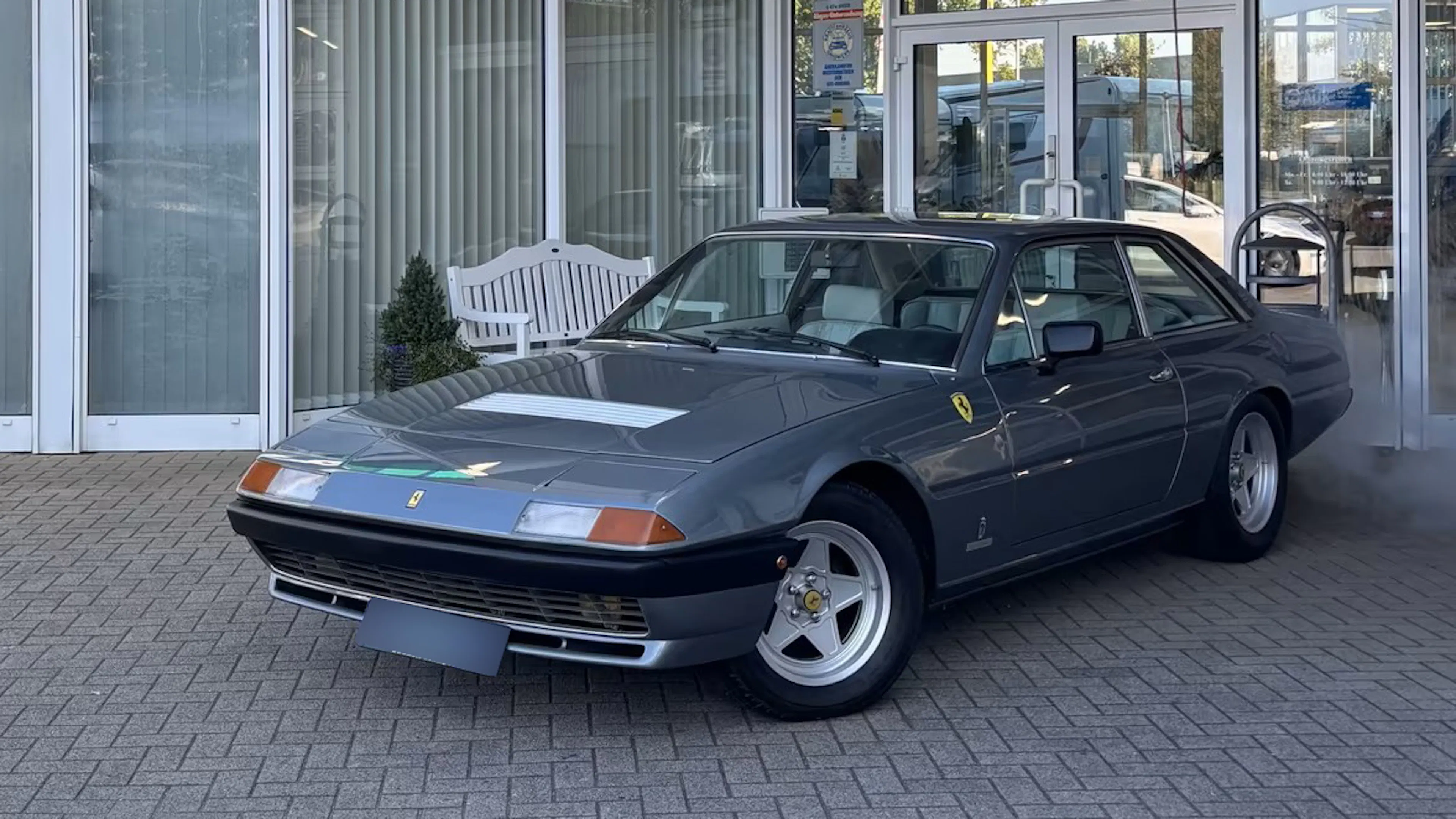 Der Ferrari 400 i V12, der einst dem Formel-1-Weltmeister Jody Scheckter gehörte, steht vor einem Autohaus.