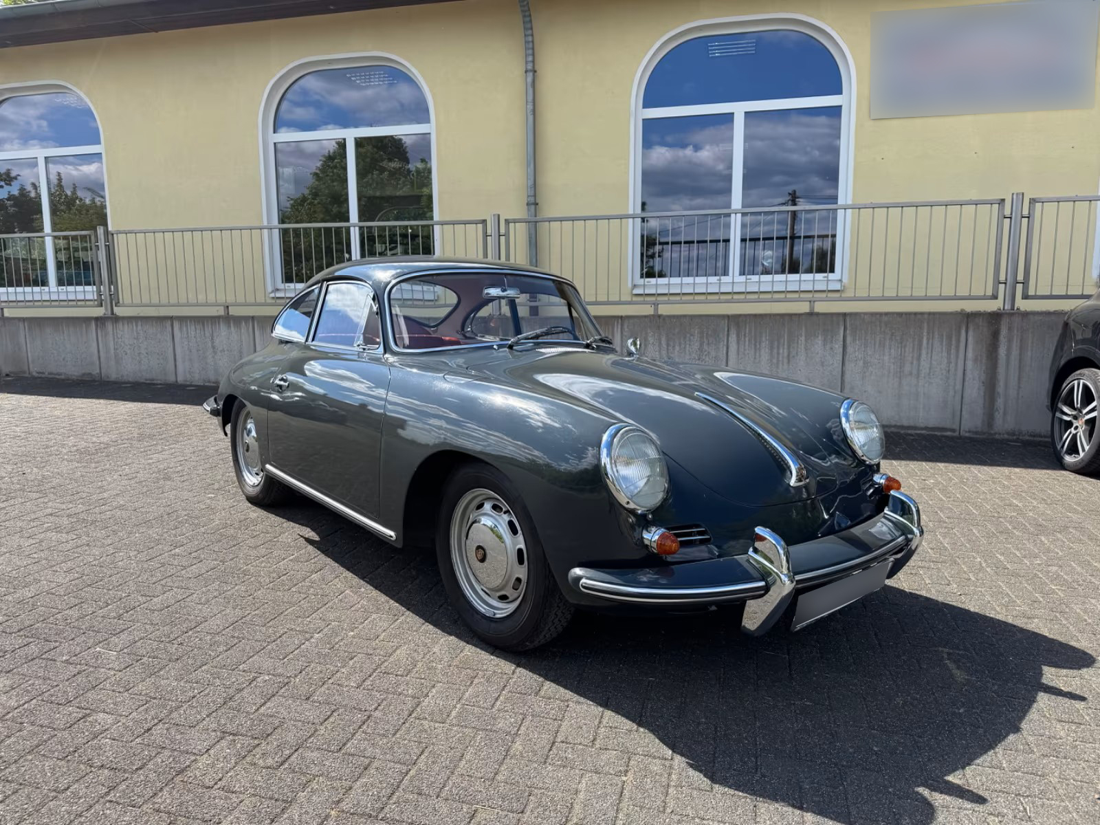 Der grau lackierte Porsche 356, der ehemals Paul Breitner gehörte, steht vor einem gelben Haus.