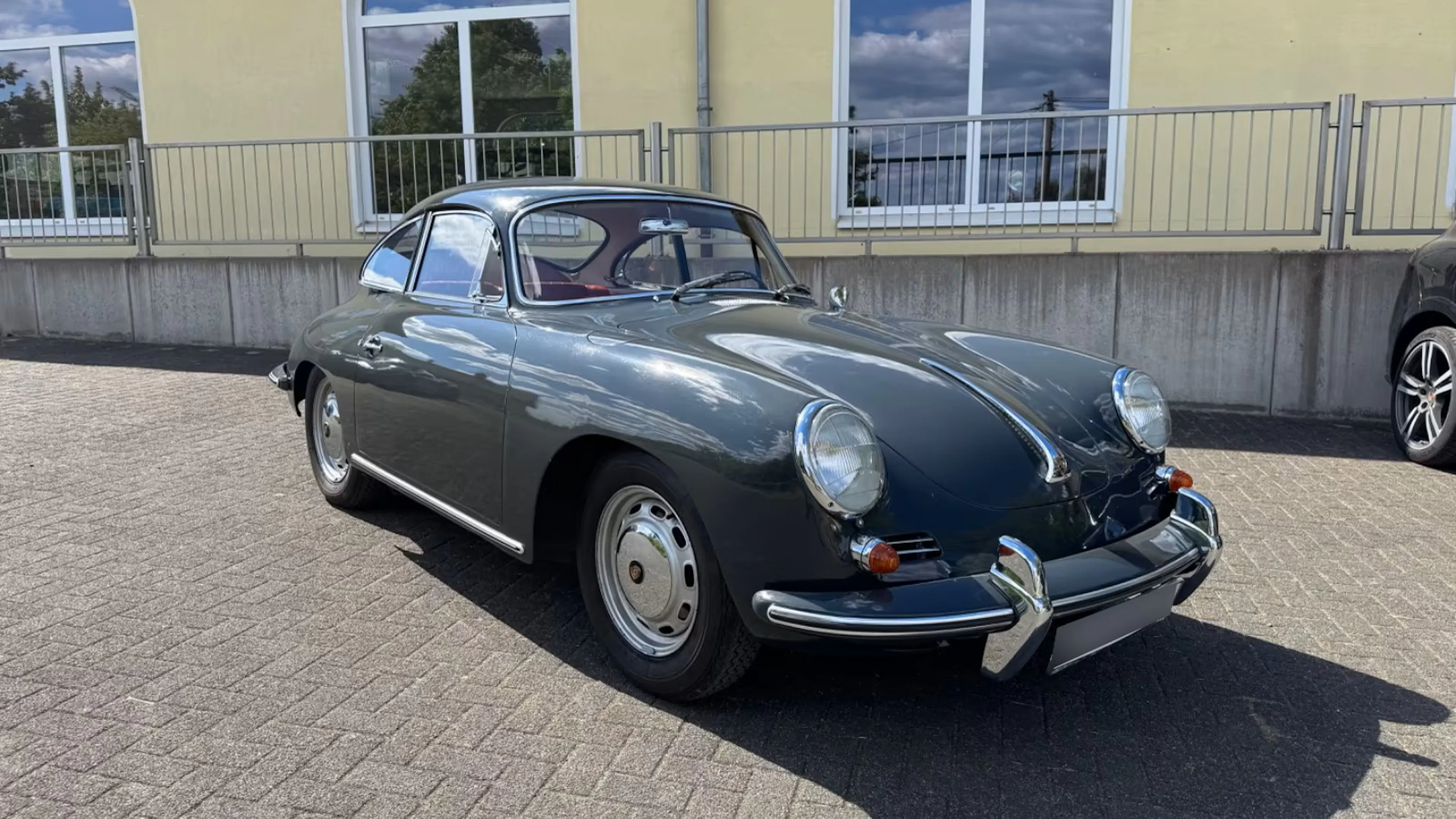 Der grau lackierte Porsche 356, der ehemals Paul Breitner gehörte, steht vor einem gelben Haus.