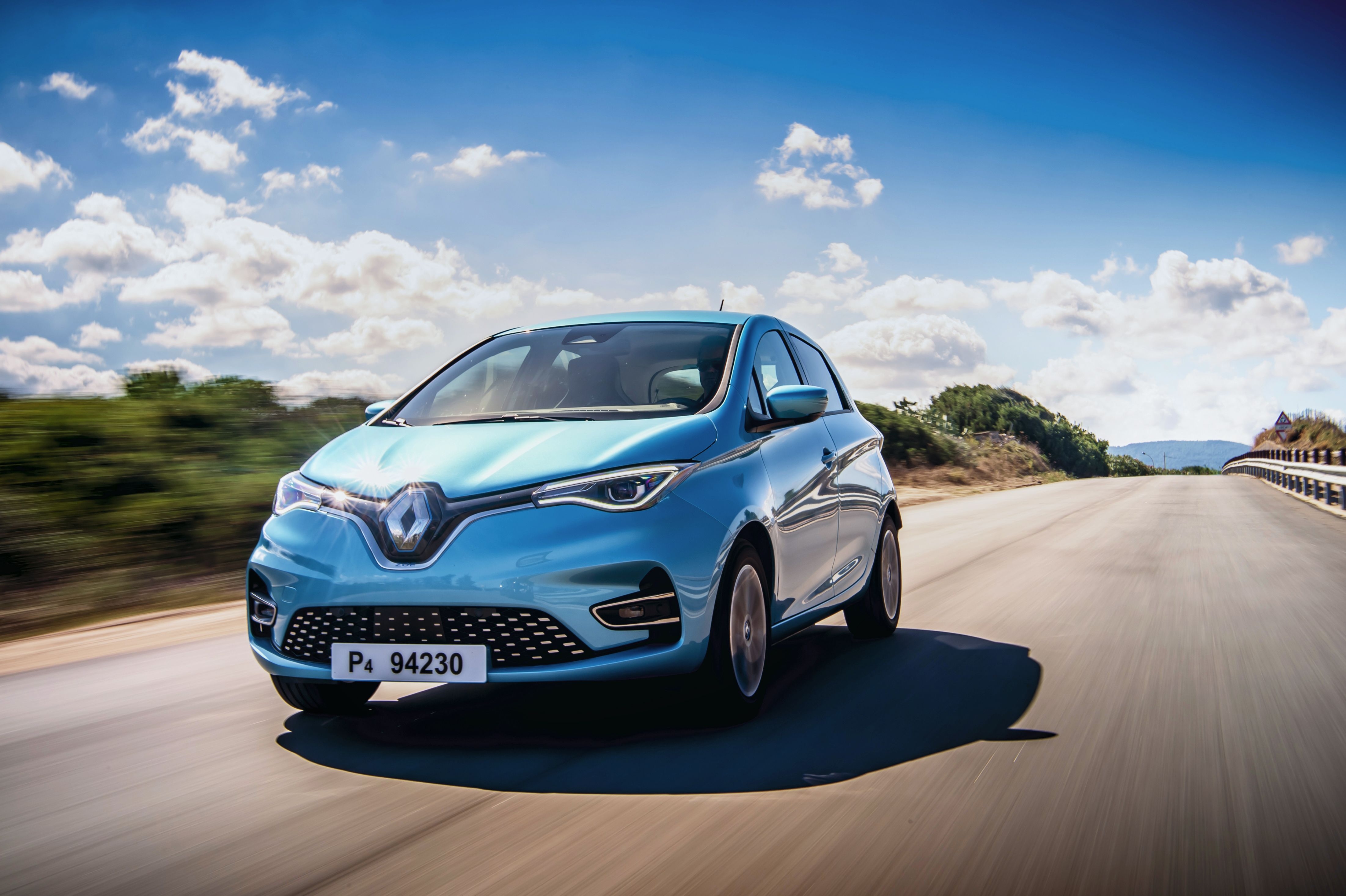 Ein hellblauer Renault Zoe fährt auf einer mediterranen Landstraße.