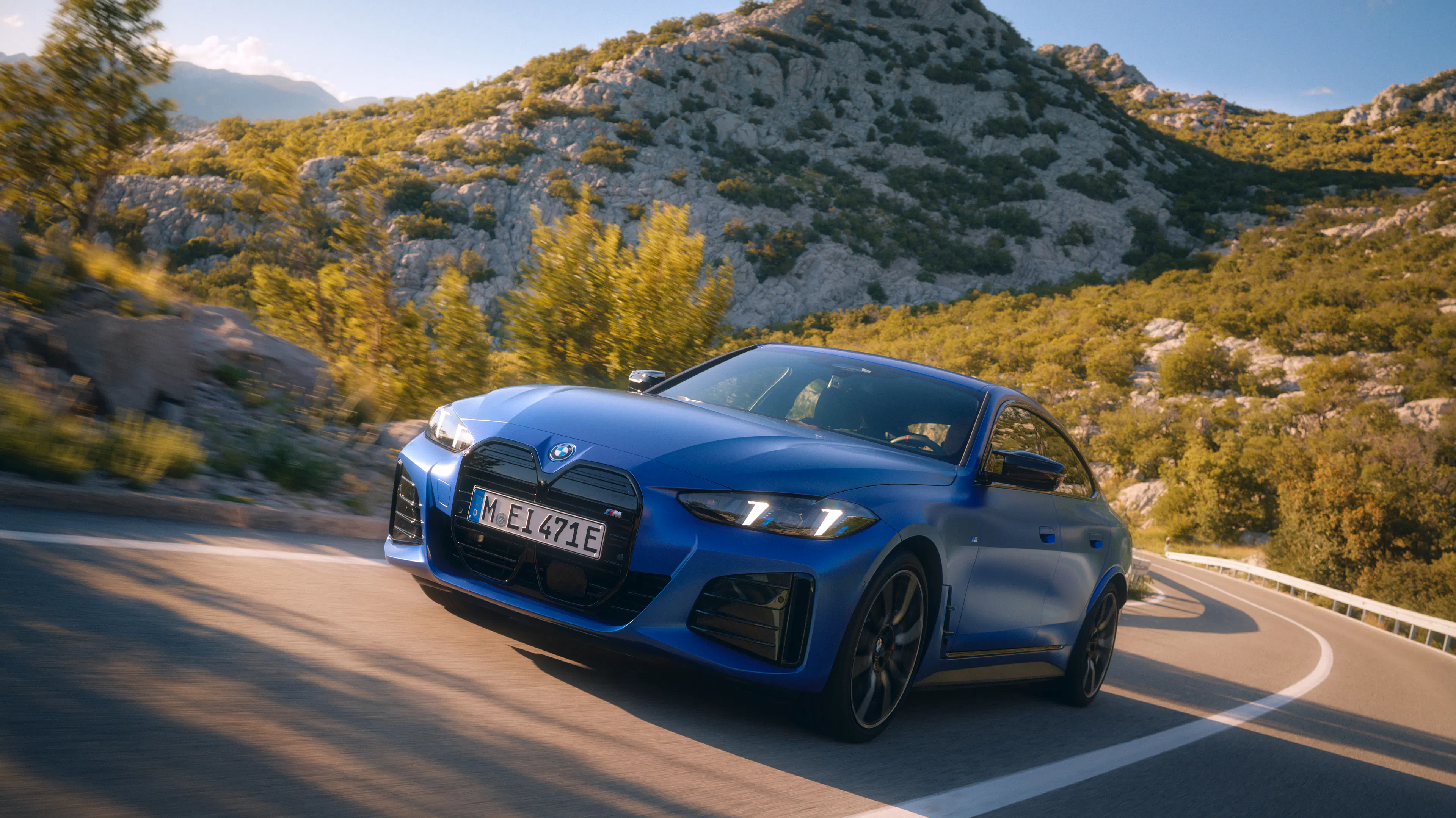 Ein blauer BMW i4 fährt auf einer Landstraße.