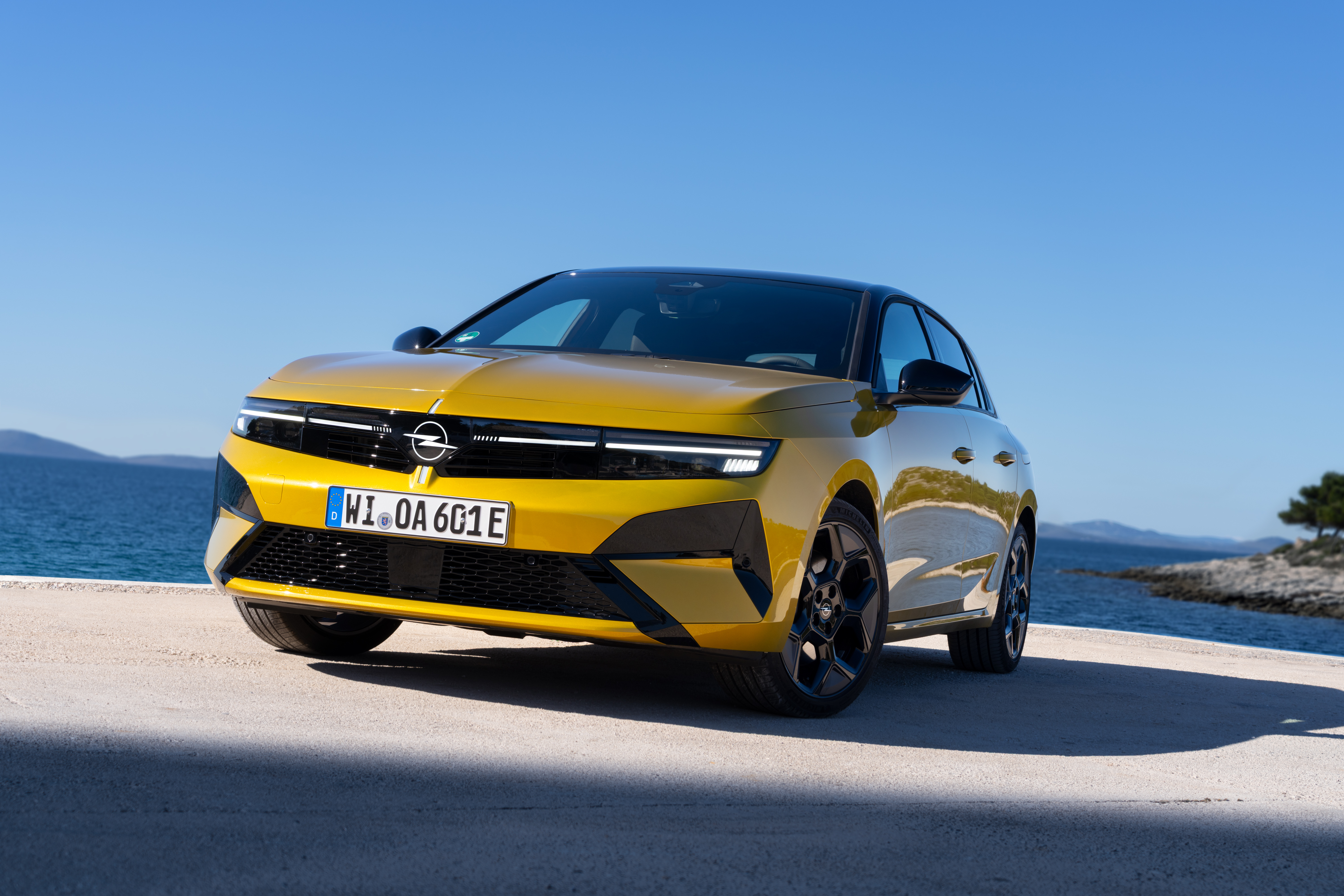 Schrägansicht von vorn des Opel Astra Plug-in-Hybrid in Gelb, stehend an einem Hafenkai.
