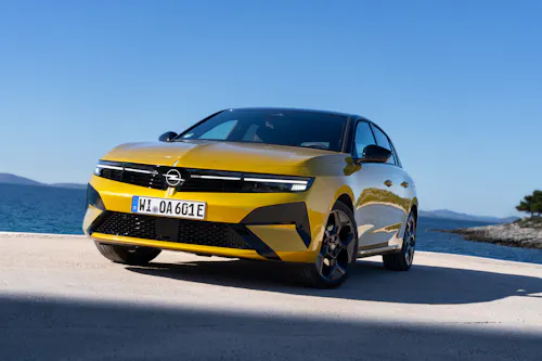 Schrägansicht von vorn des Opel Astra Plug-in-Hybrid in Gelb, stehend an einem Hafenkai.