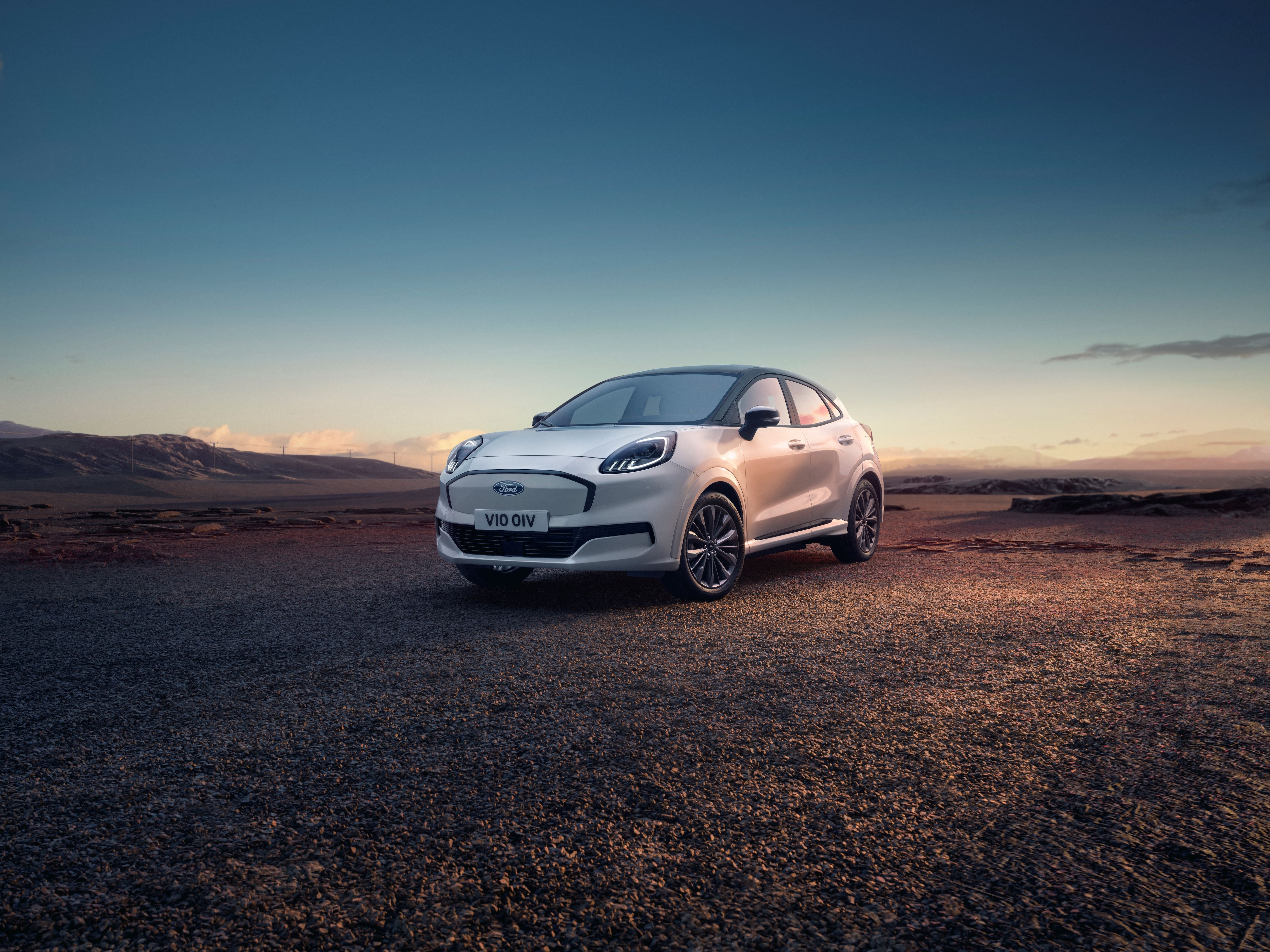Ein silberner Ford Puma Gen-E steht auf einem freien Feld.