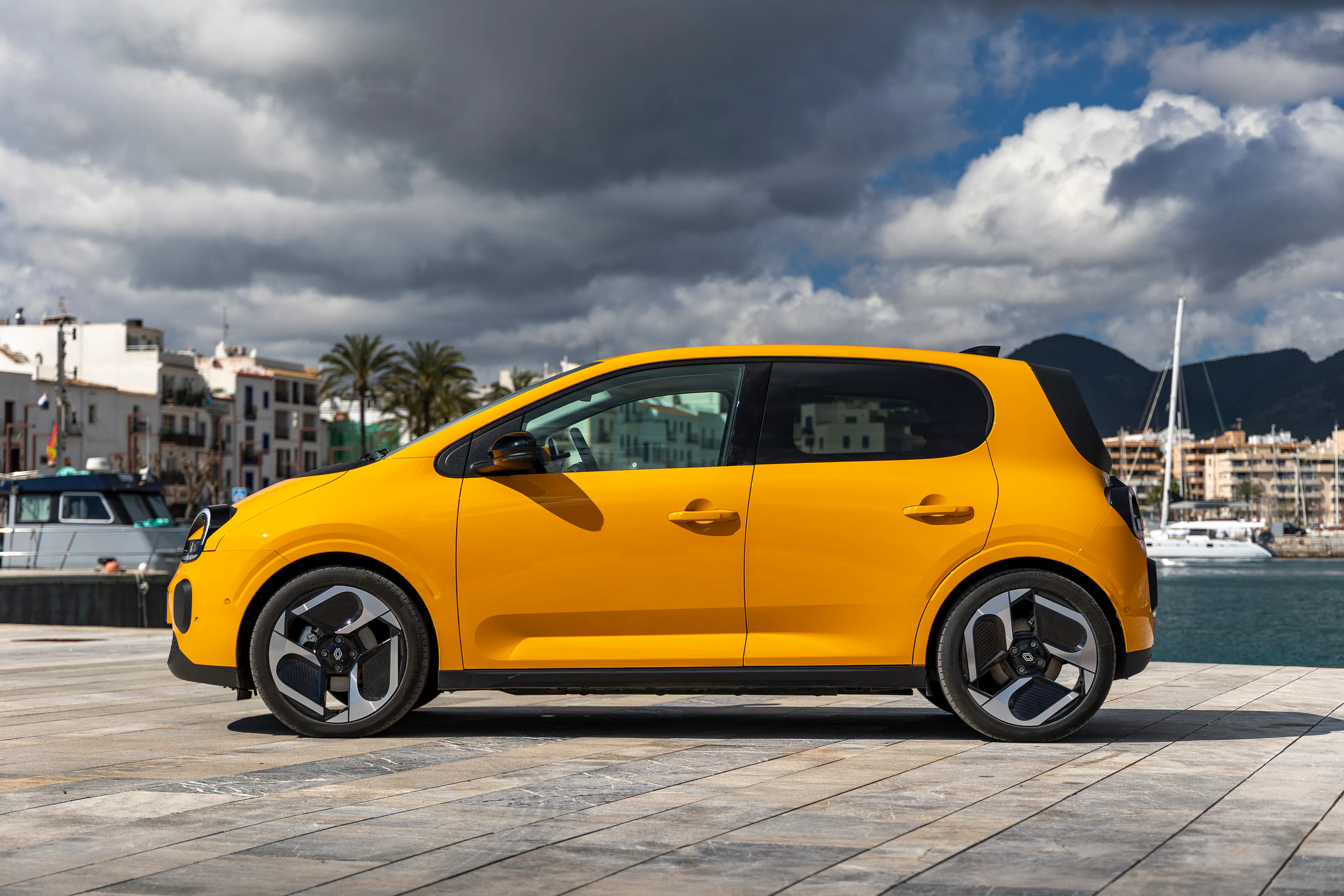 Ein gelber Renault Twingo E-Tech Electric steht an einer Hafenpromenade.