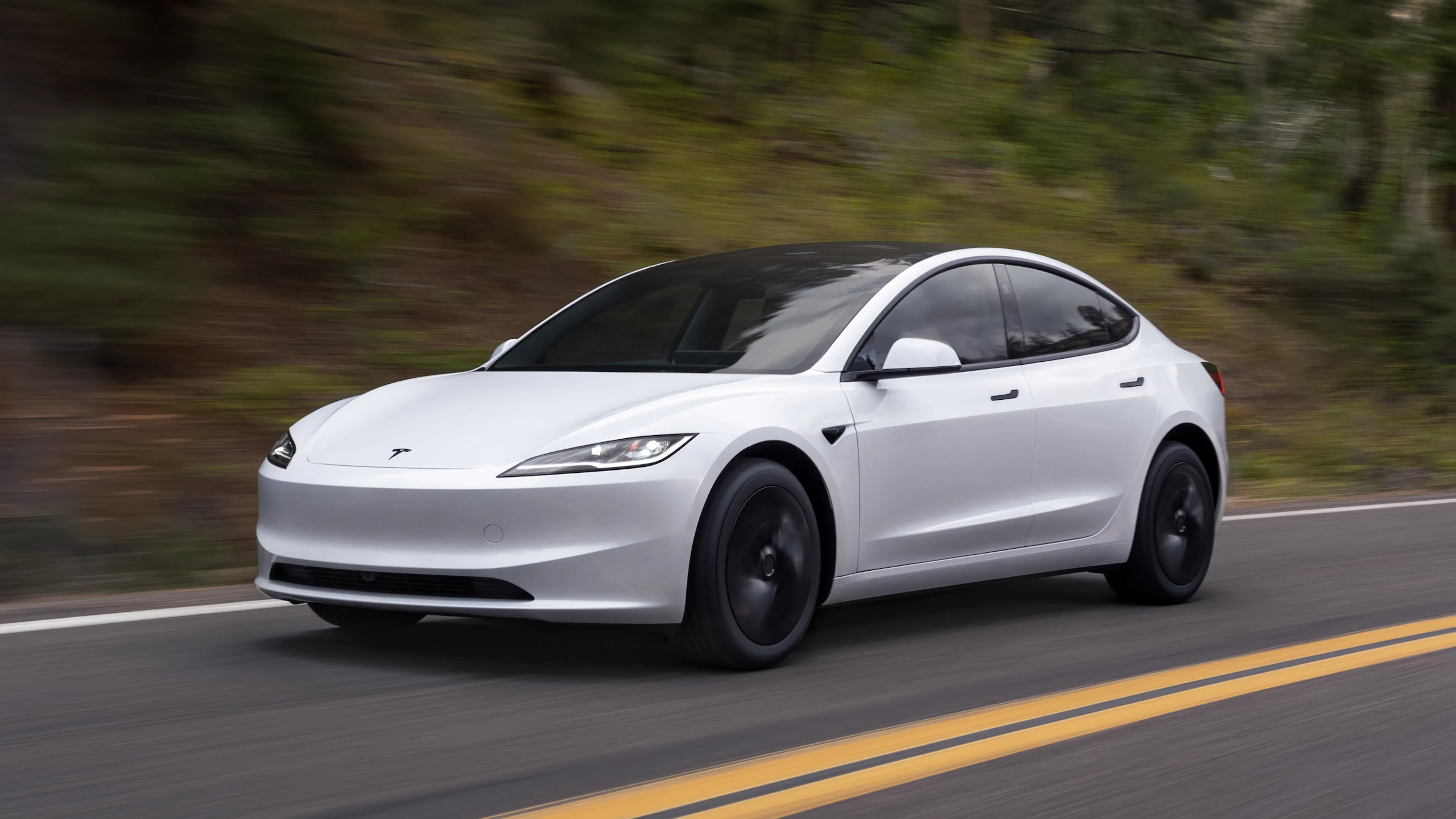 Ein weißer Tesla Model 3 fährt auf einer Landstraße in den USA.