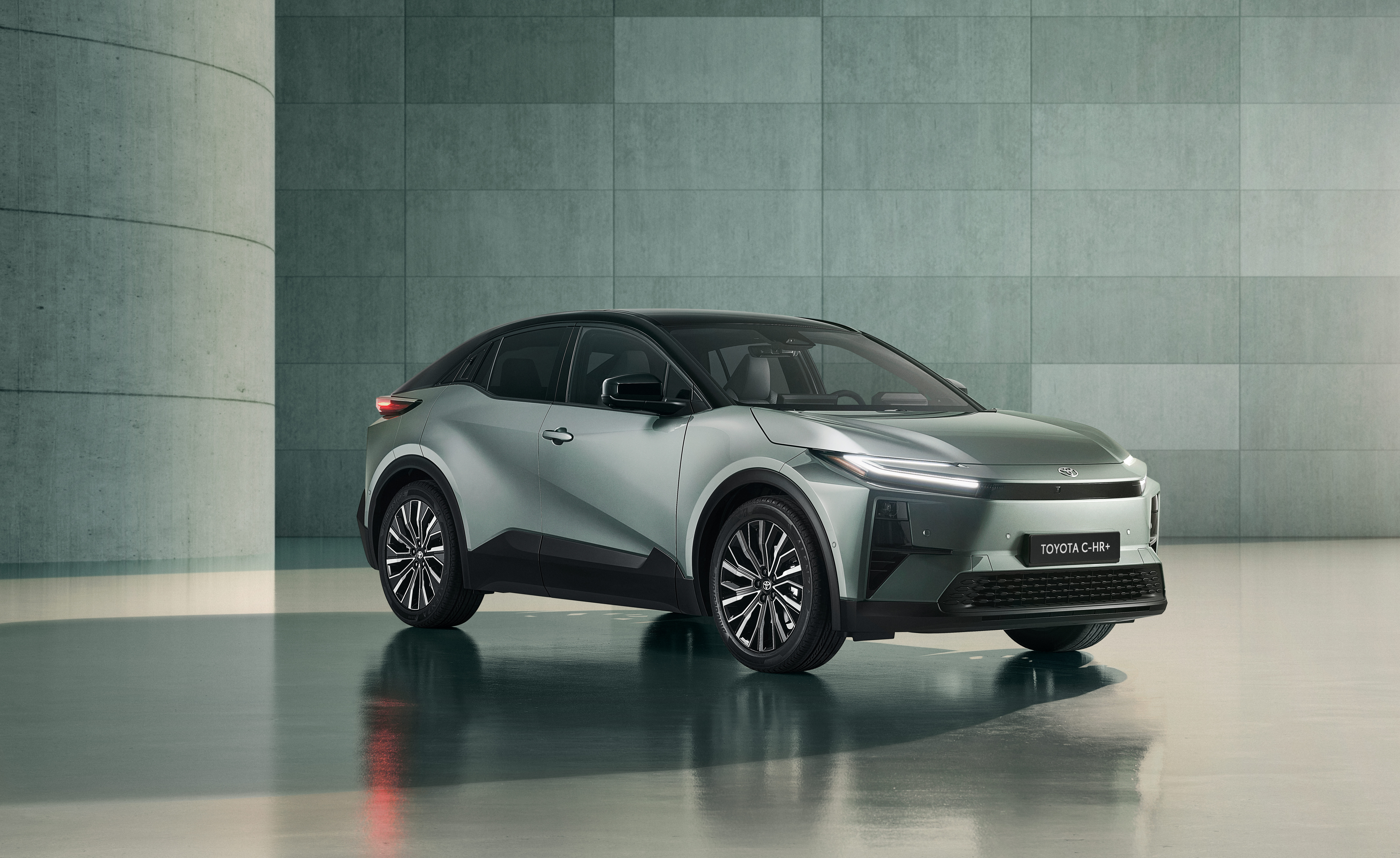 Ein silberner Toyota C-HR+ steht in einem Raum mit Betonwand.