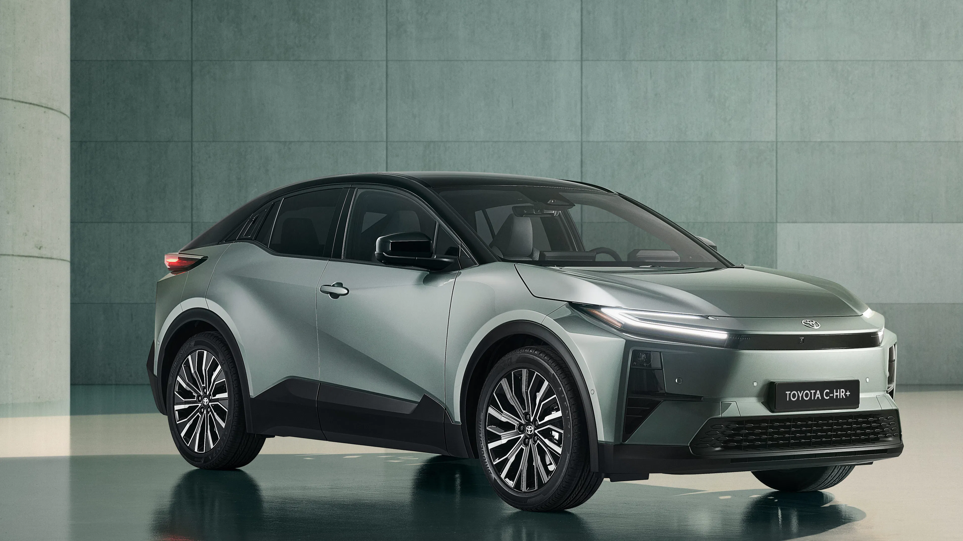 Ein silberner Toyota C-HR+ steht in einem Raum mit Betonwand.