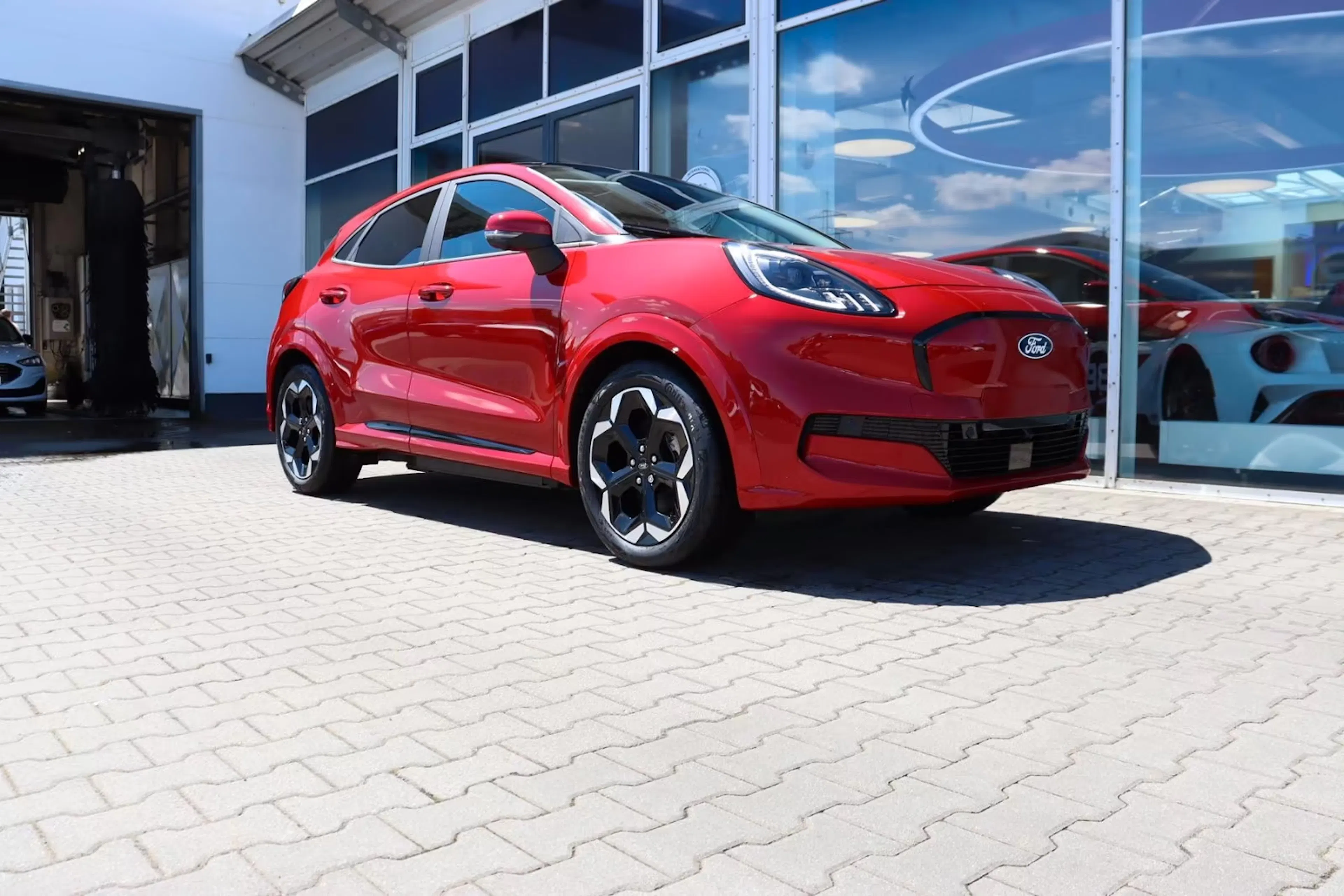 Ein roter Ford Puma Gen-E steht vor einem Autohaus.