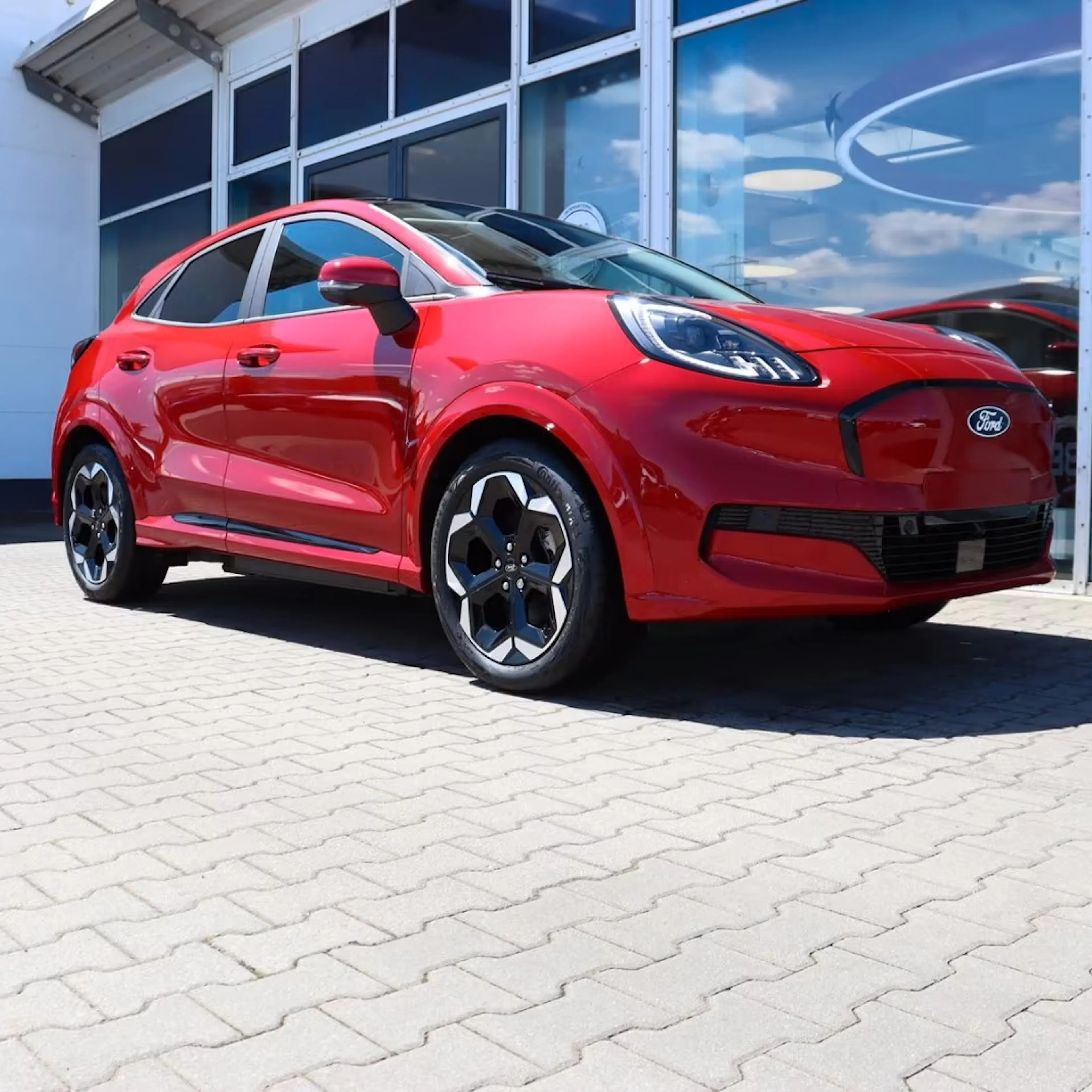 Ein roter Ford Puma Gen-E steht vor einem Autohaus.