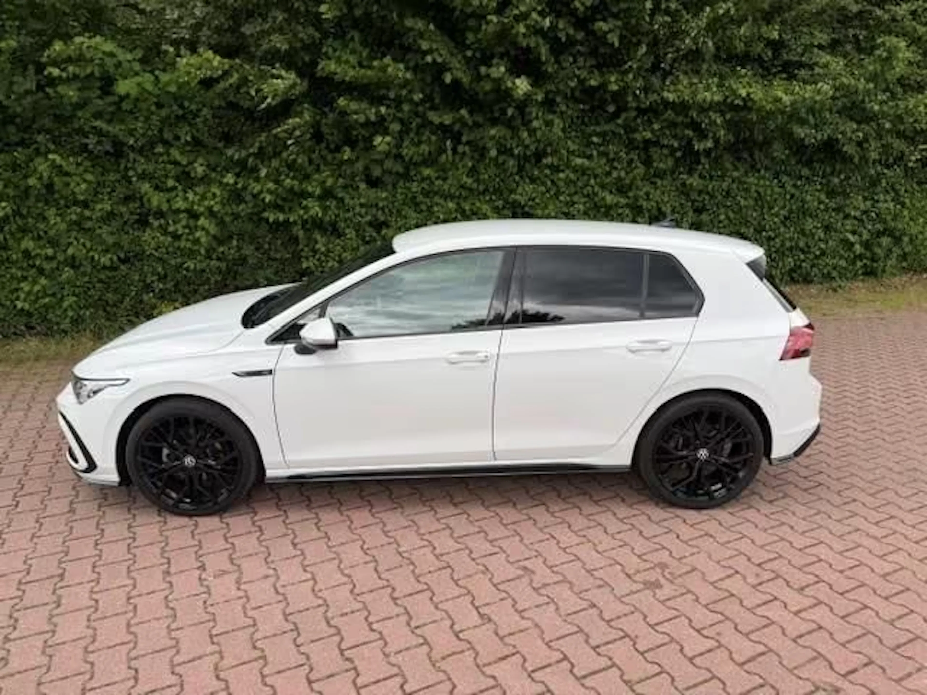 Ein weißer Golf eTSI steht auf einer gepflasterten Fläche.