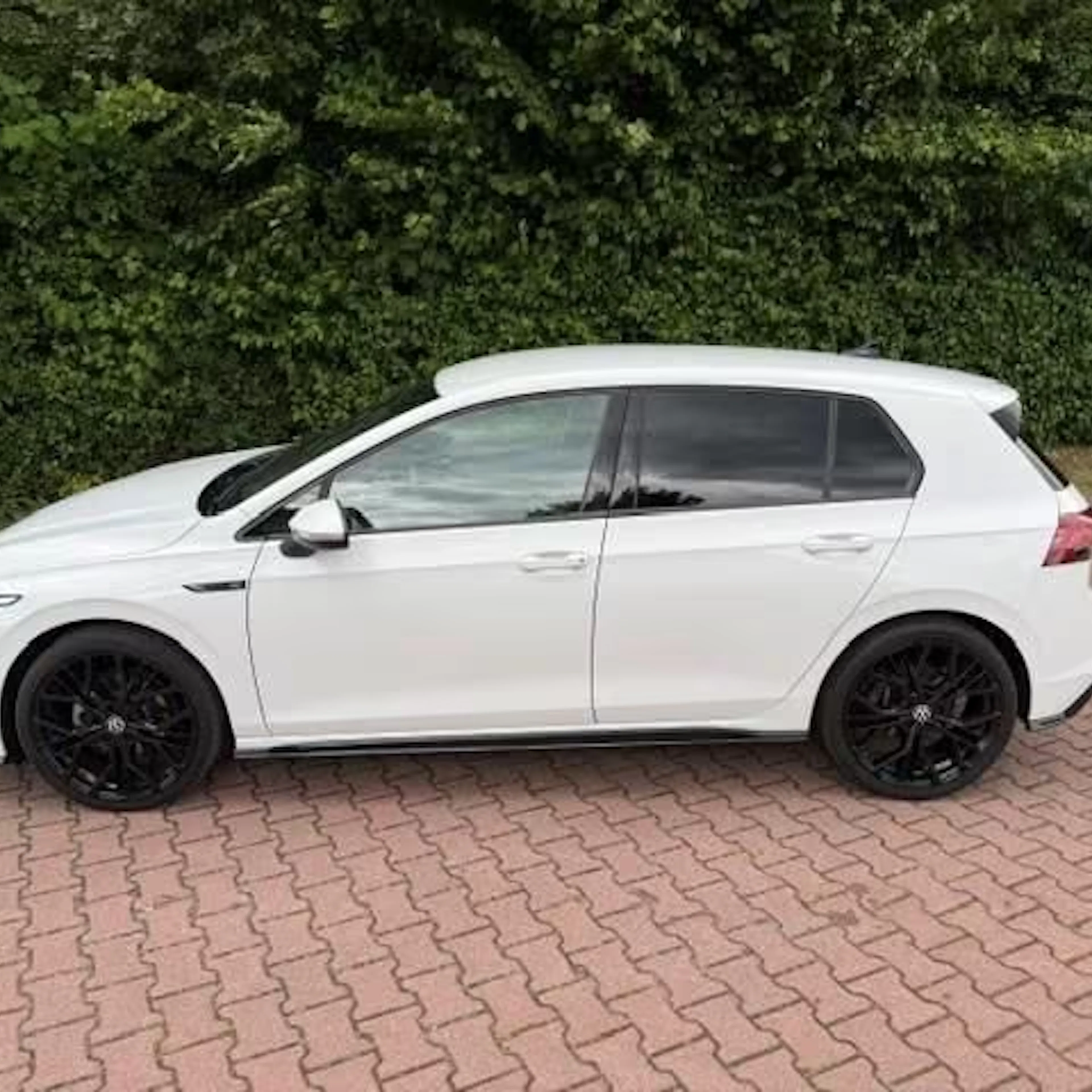 Ein weißer Golf eTSI steht auf einer gepflasterten Fläche.
