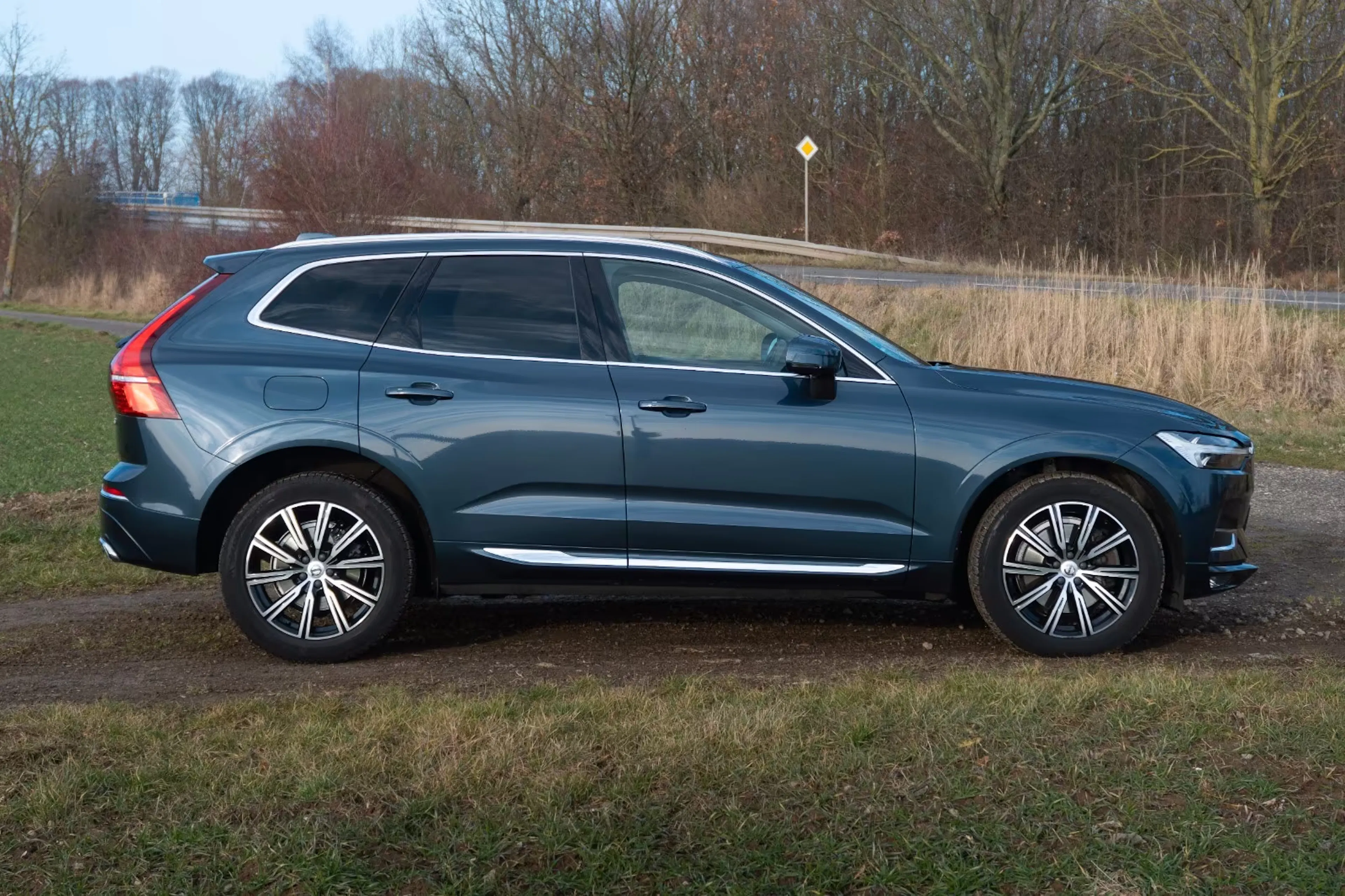 Ein dunkelblauer Volvo XC60 steht auf einer bewachsenen Fläche.