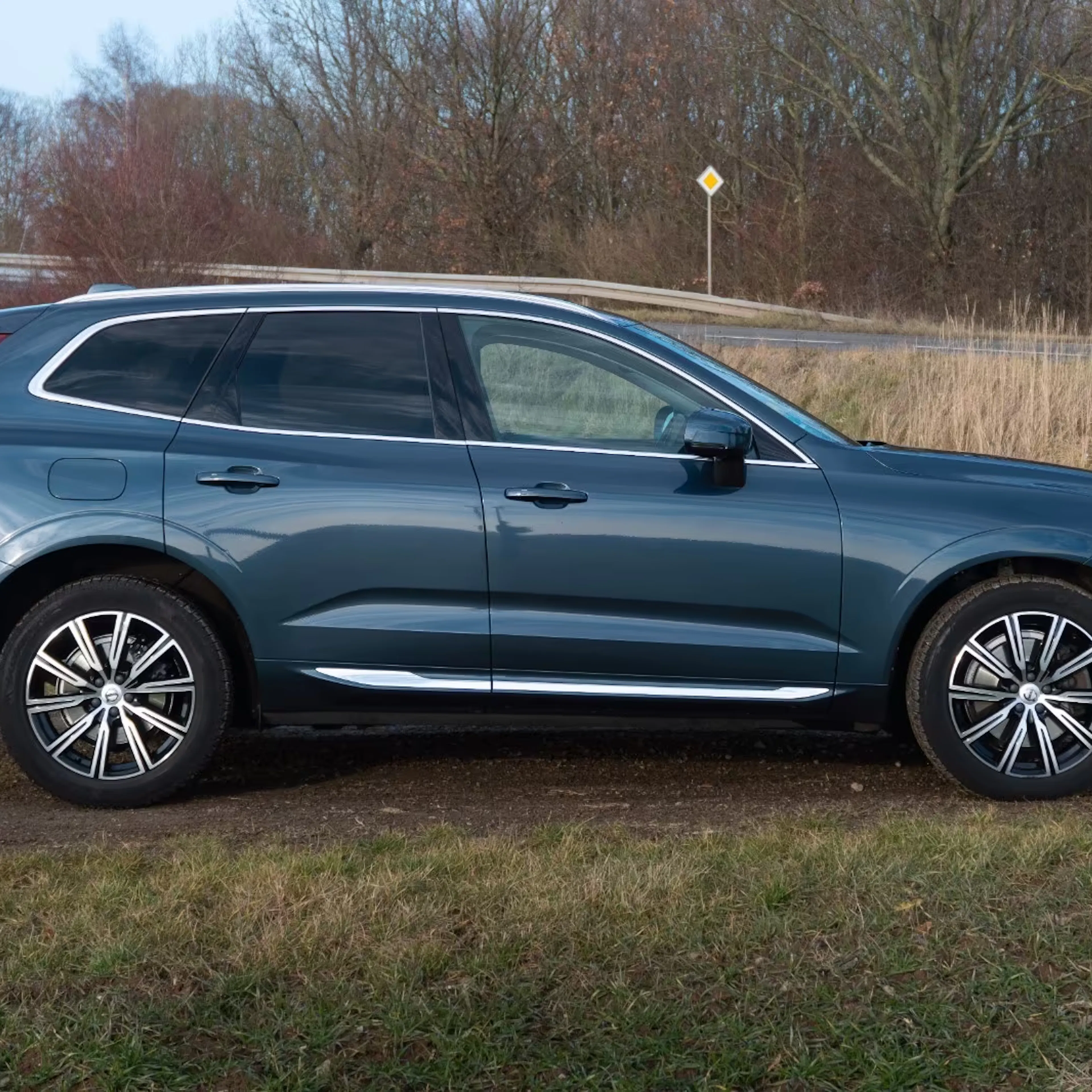Ein dunkelblauer Volvo XC60 steht auf einer bewachsenen Fläche.