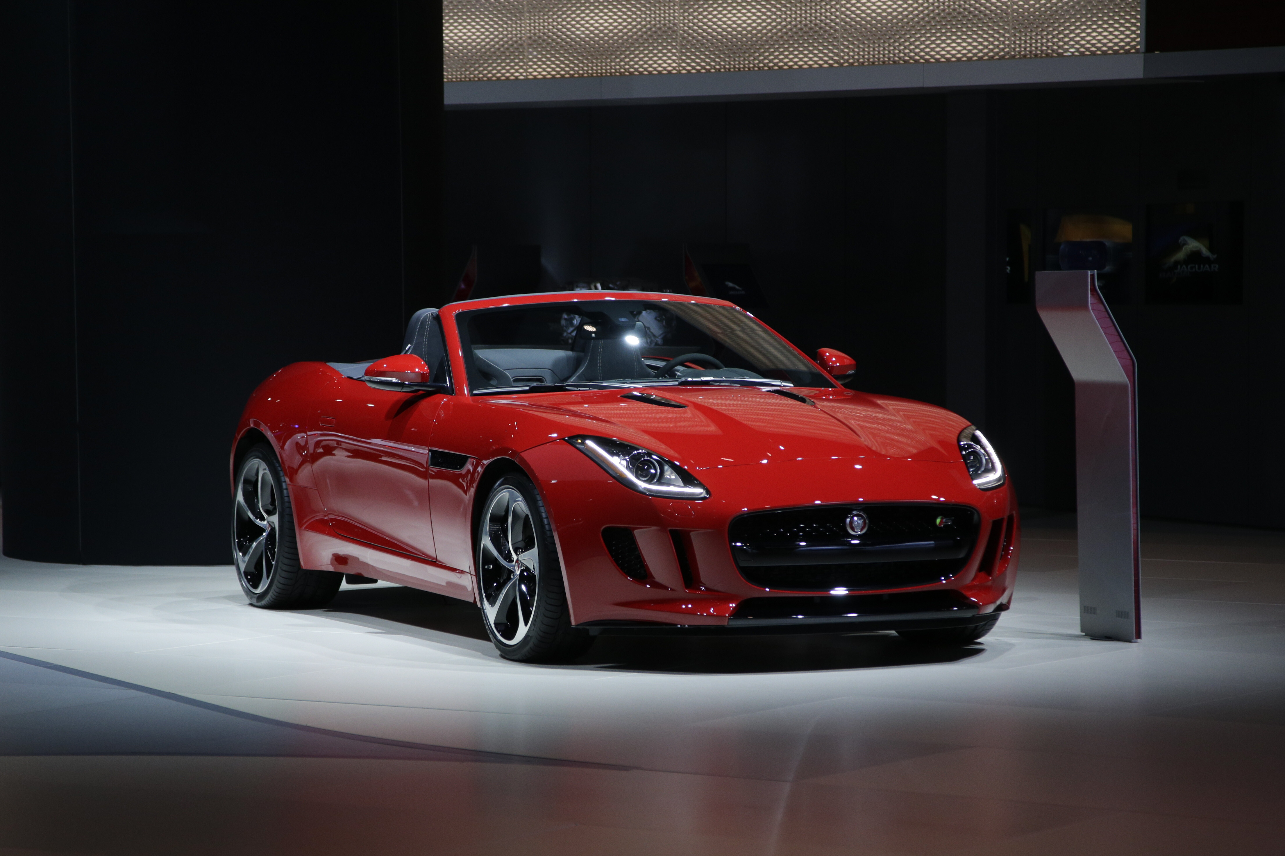 Ein roter Jaguar F-Type S steht auf einer Präsentationsfläche im Scheinwerferlicht.