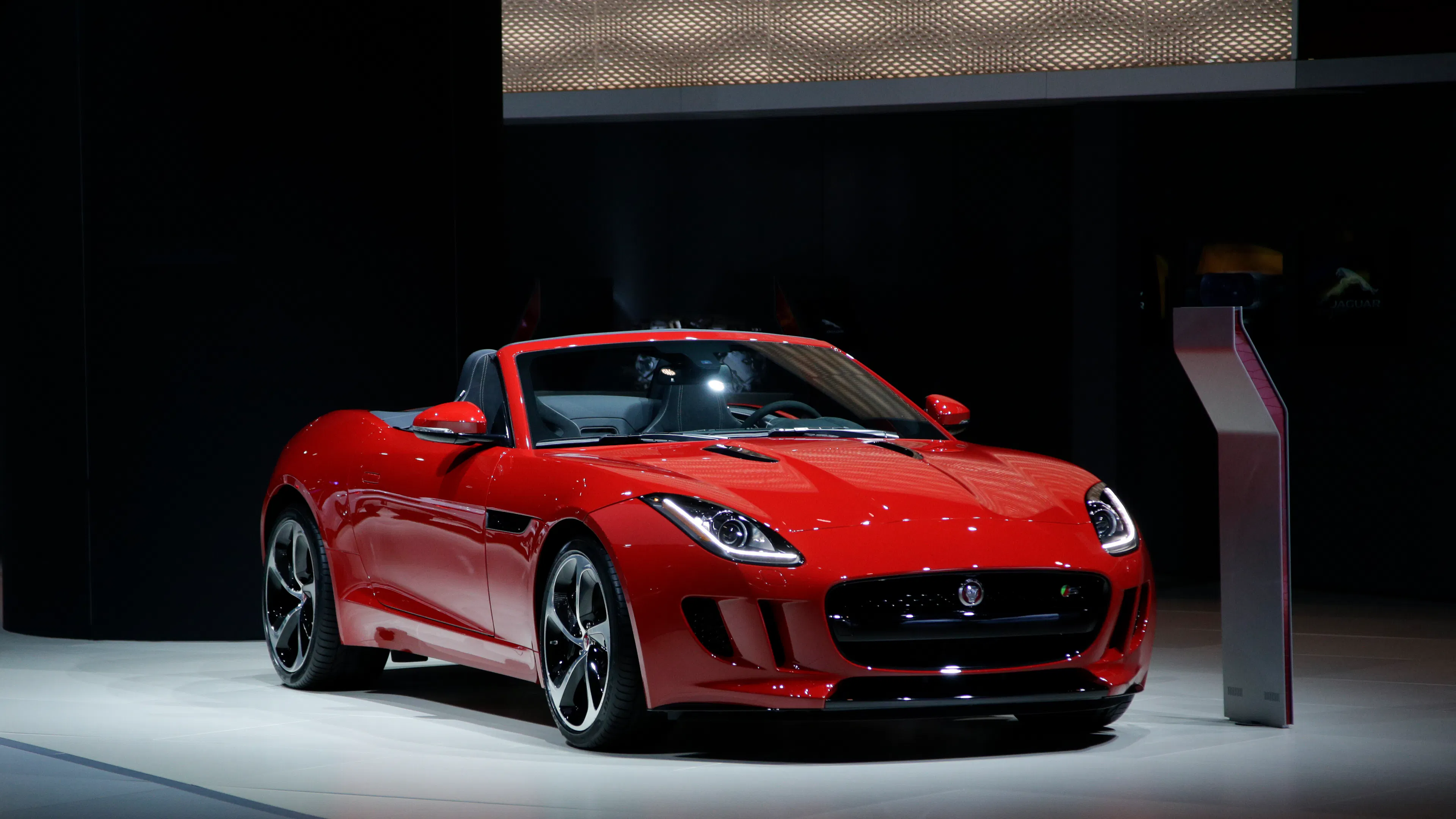 Ein roter Jaguar F-Type S steht auf einer Präsentationsfläche im Scheinwerferlicht.