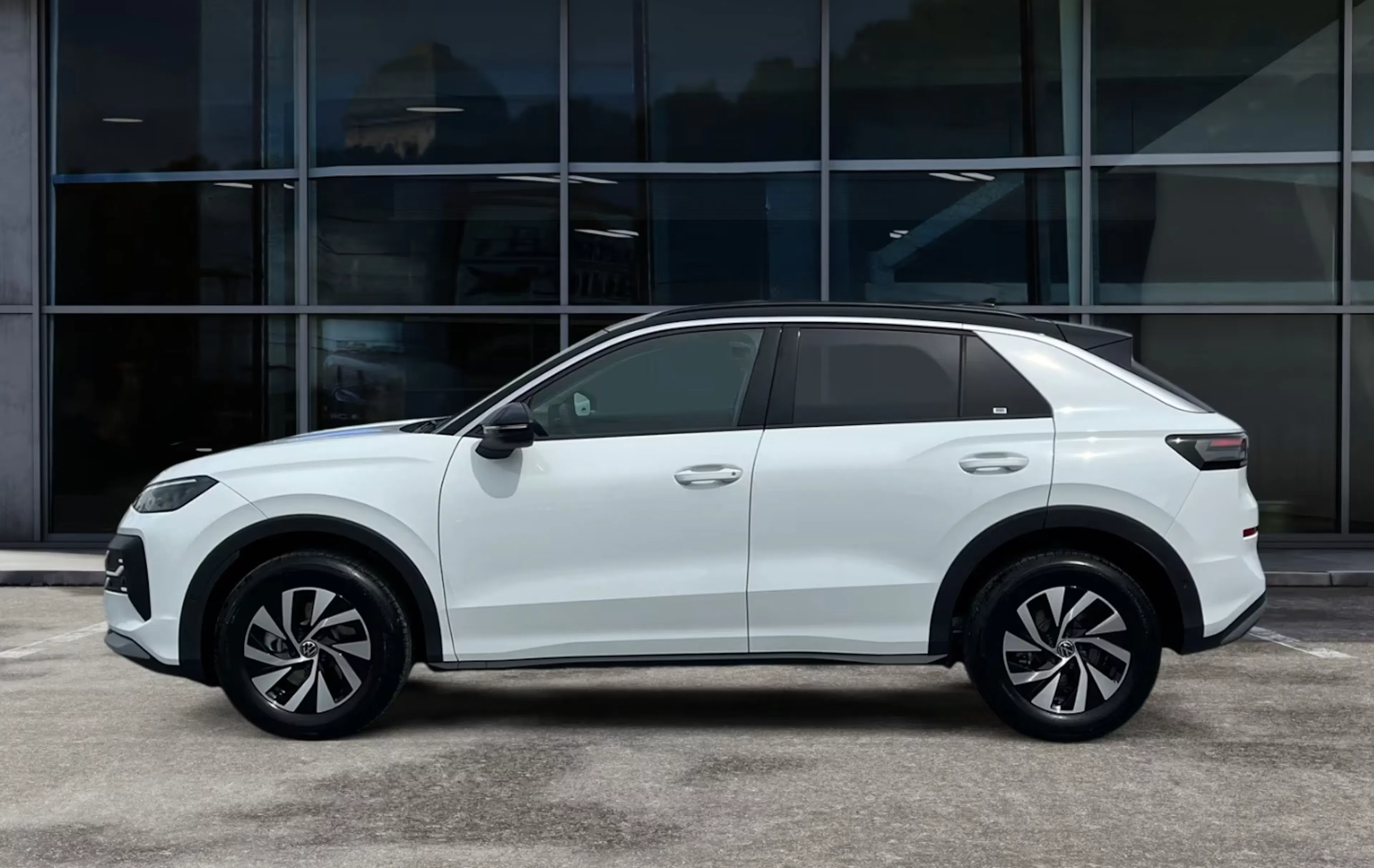 Ein weißer VW T-Roc steht auf einer gepflasterten Fläche.