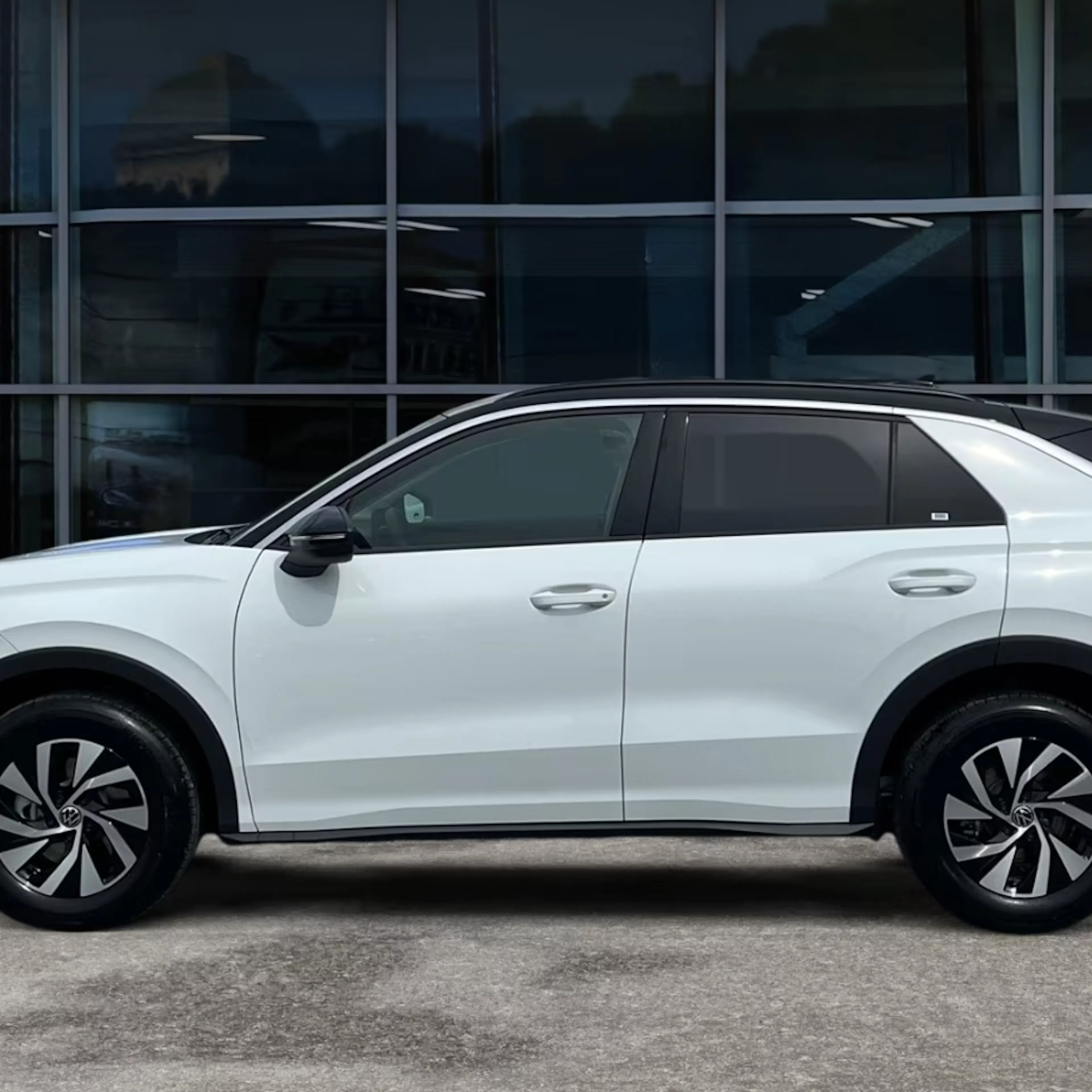 Ein weißer VW T-Roc steht auf einer gepflasterten Fläche.