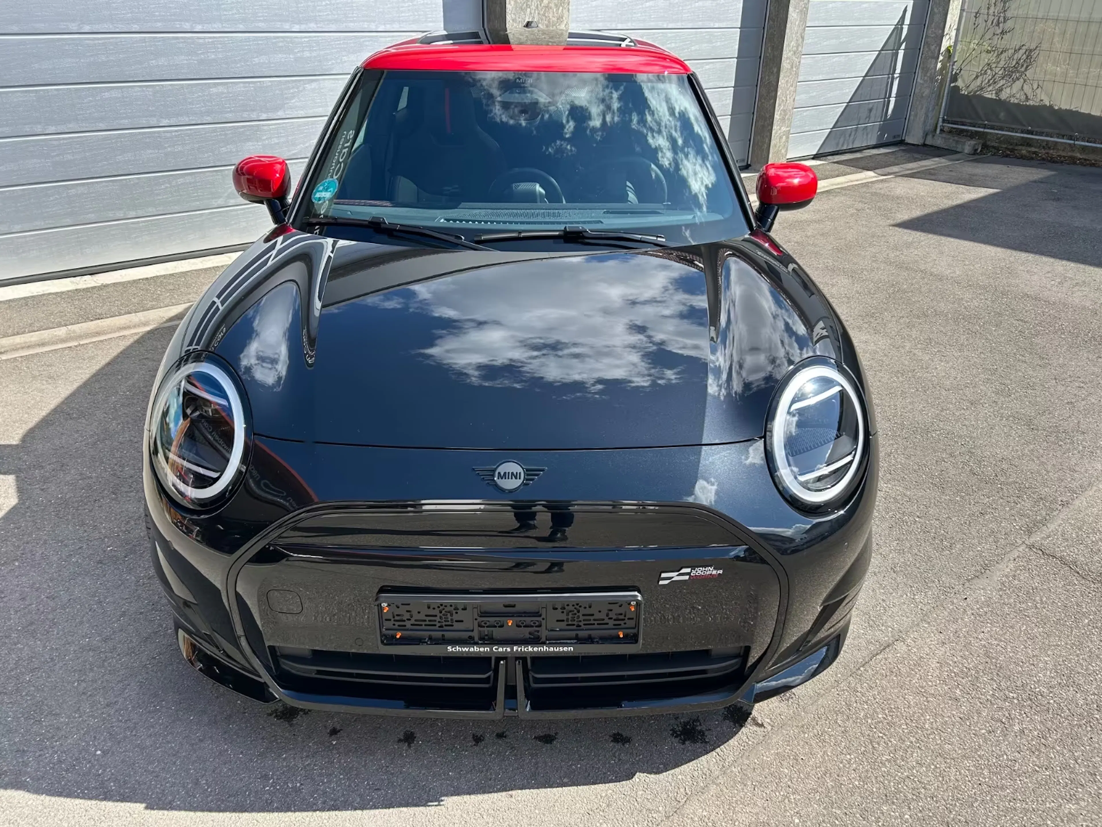 Ein Mini Cooper SE John Cooper Works steht auf einer gepflasterten Fläche.