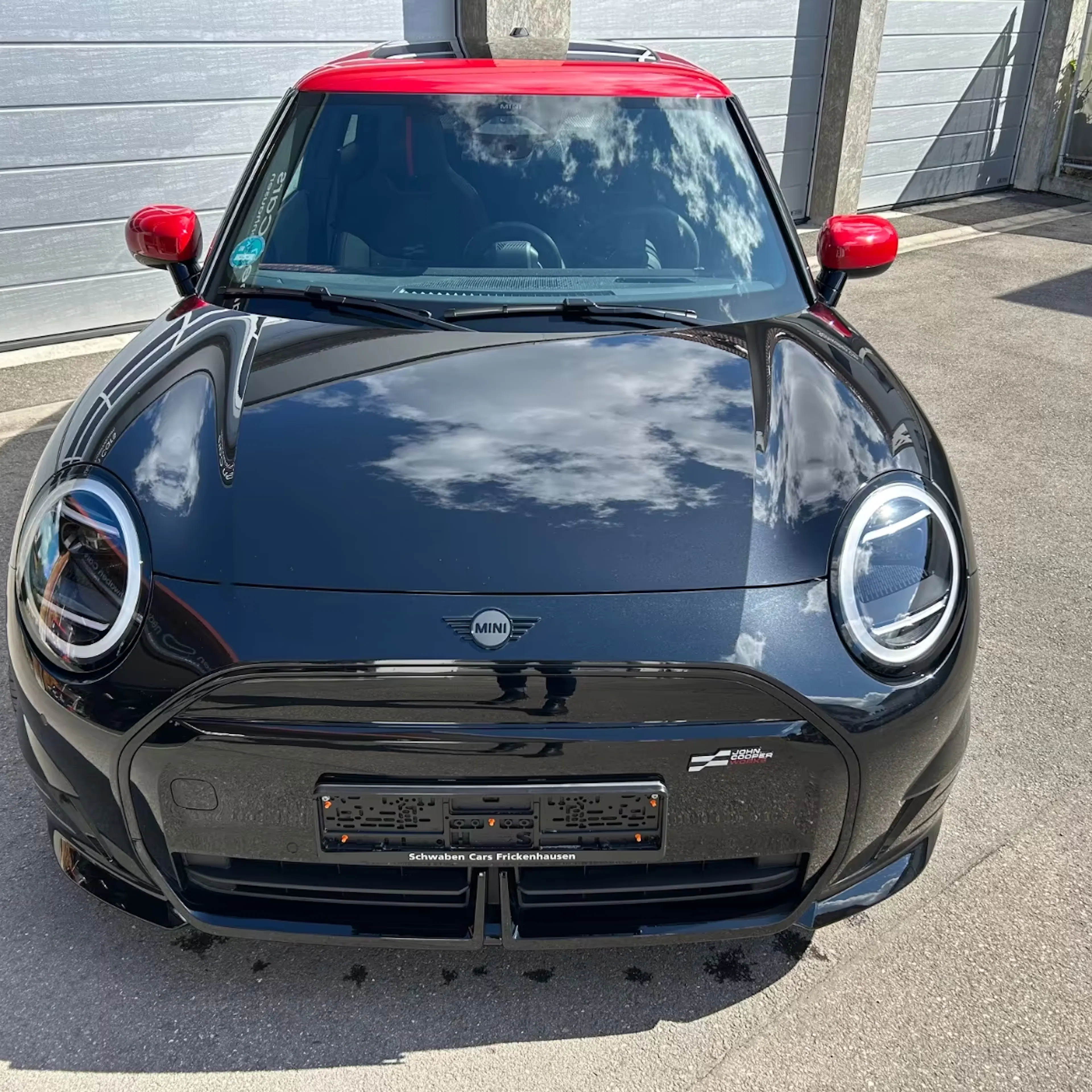 Ein Mini Cooper SE John Cooper Works steht auf einer gepflasterten Fläche.