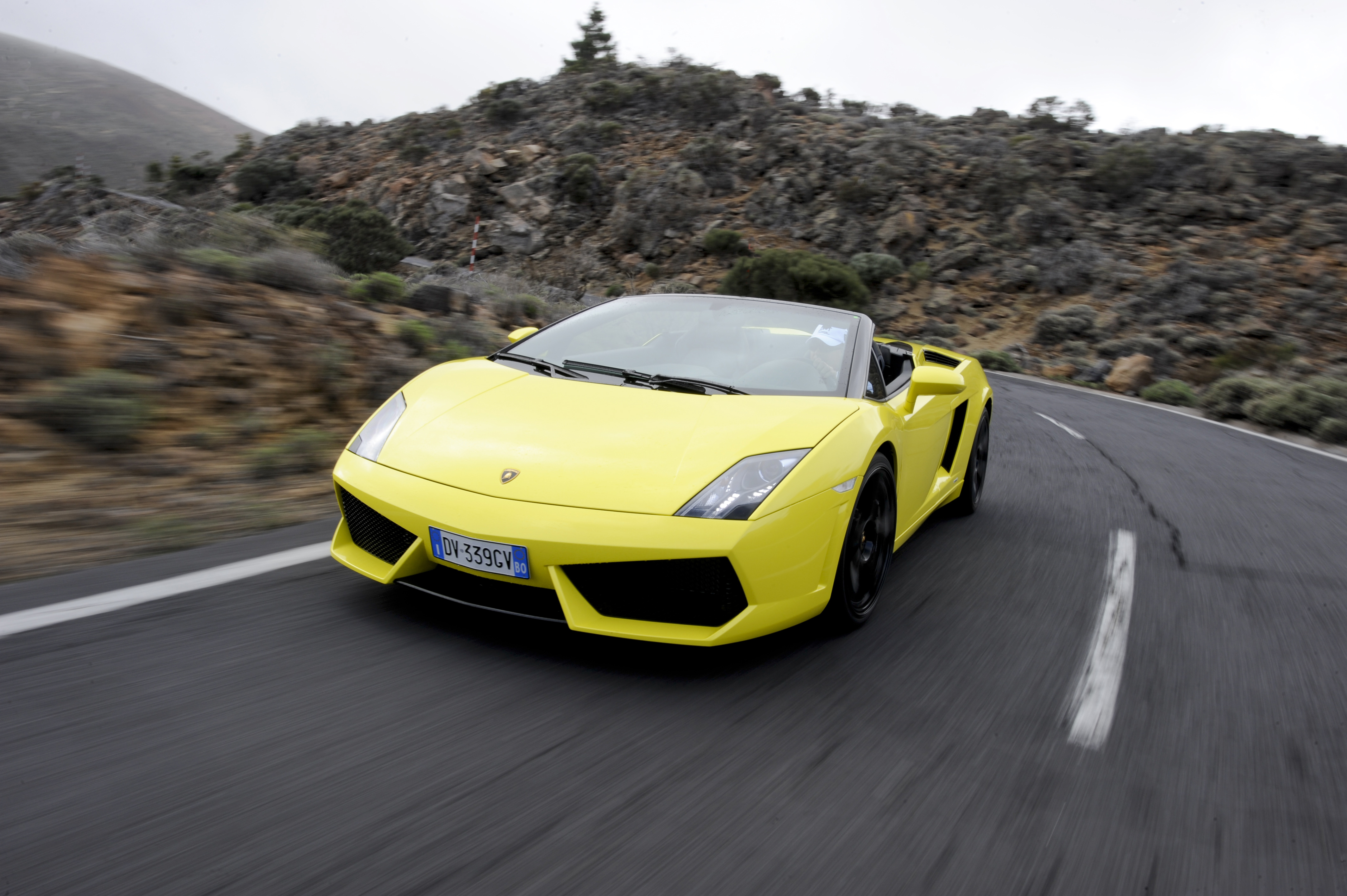 Ein gelber Lamborghini Gallardo Spyder fährt auf einer Landstraße.