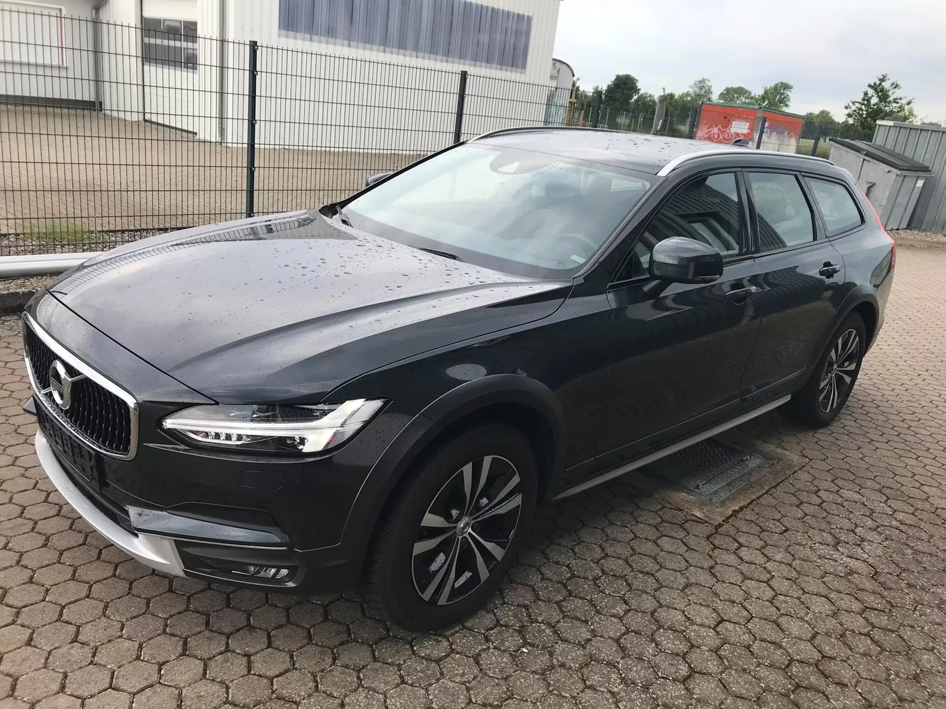 Ein schwarzer Volvo V90 Cross Country steht auf einem gepflasterten Platz