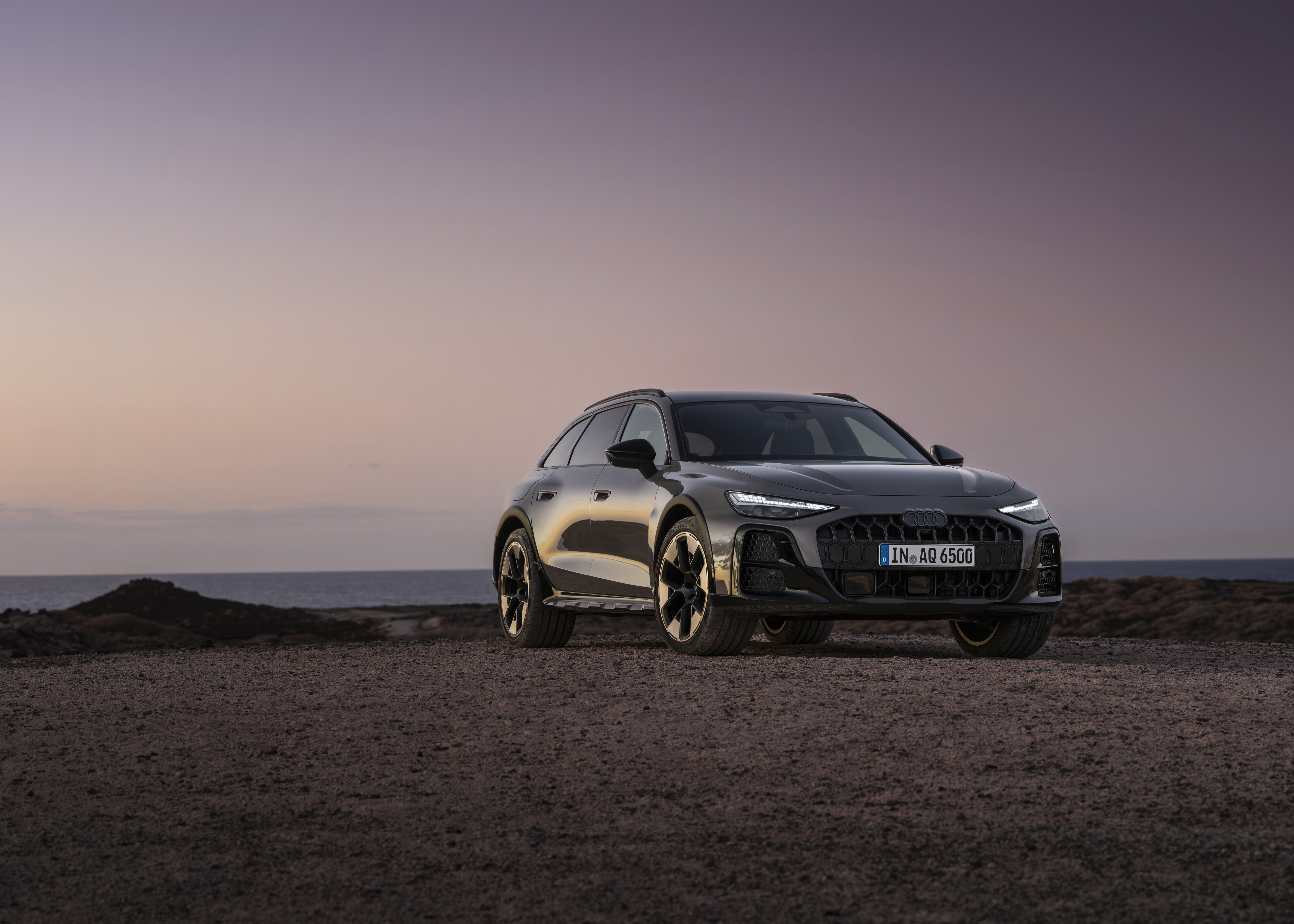 Ein dunkelgrauer Audi A6 Allroad steht auf einer freien Fläche.