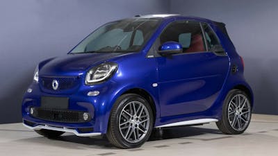 Ein blaues Smart EQ Fortwo Cabrio steht vor einer grau-blauen Wand.