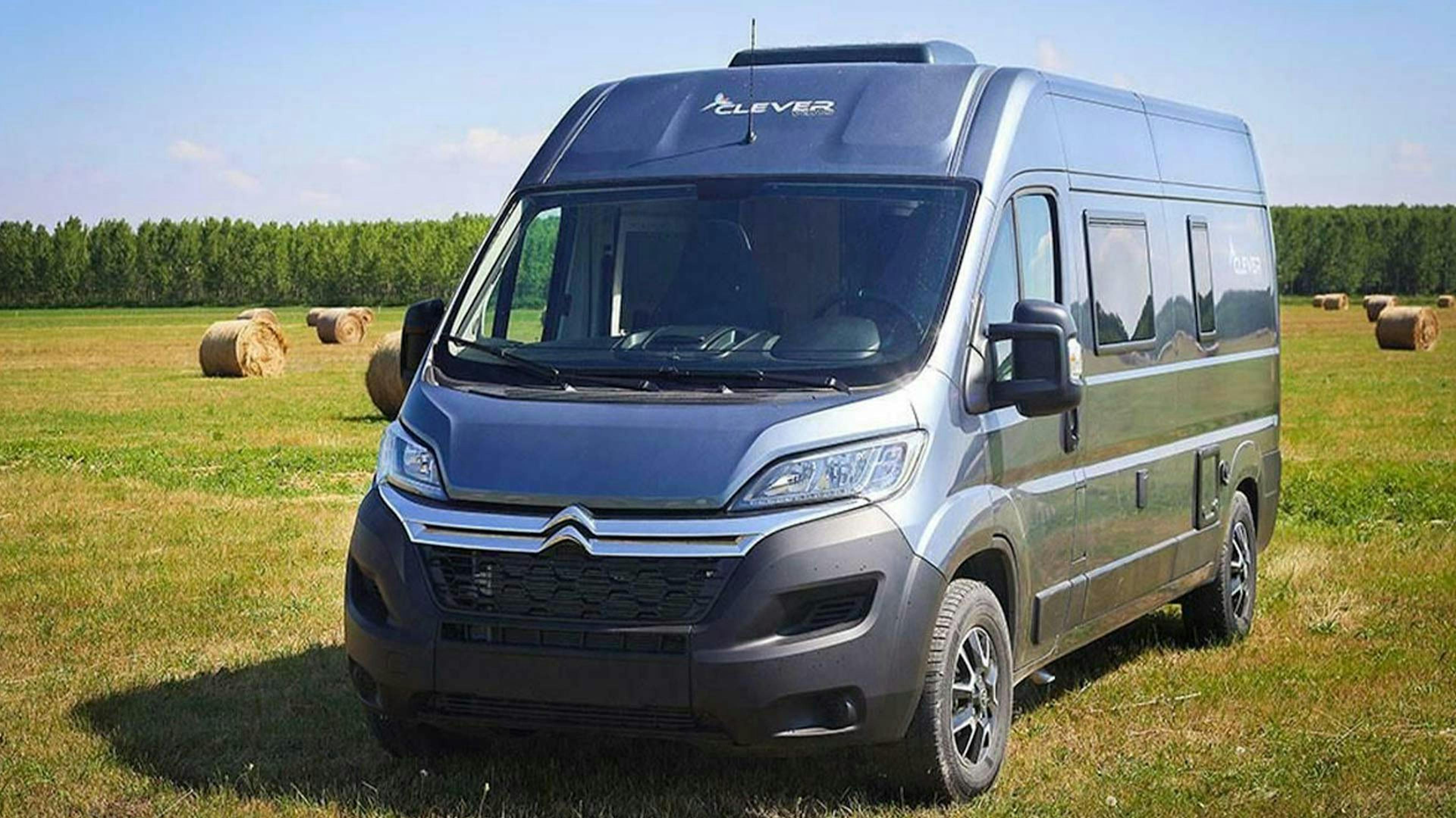 Ein günstiges graues Clever Vans Vario Kids 600 Wohnmobil steht auf einer grünen Wiese