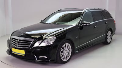 Ein schwarzer Mercedes-Benz AMG steht vor einer weißen Wand