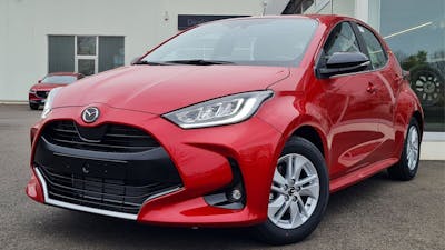 Ein roter Madza2 steht vor einem Autohaus.