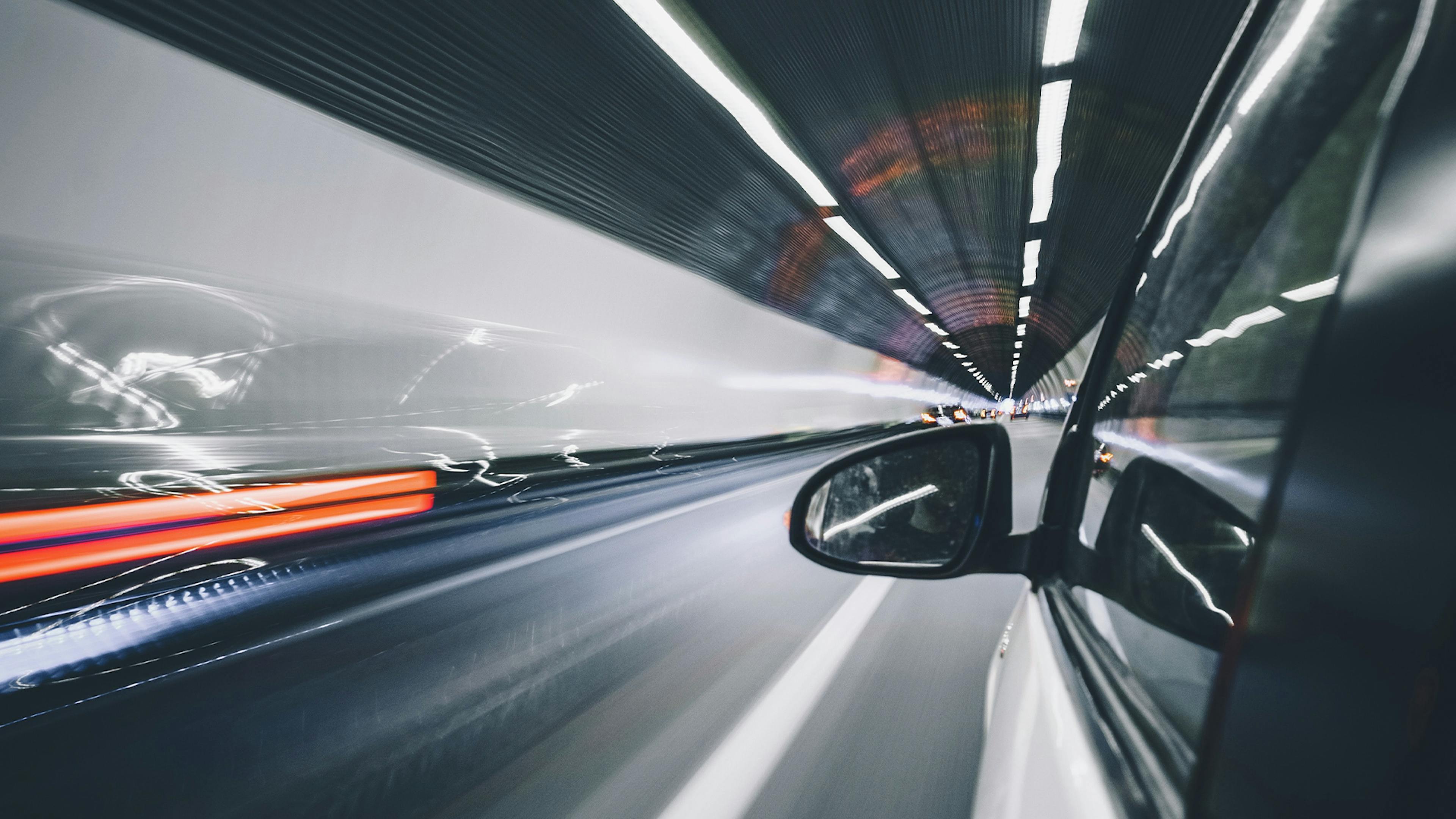 Blick aus dem Fenster eines Autos, das mit hoher Geschwindigkeit durch einen Tunnel fährt.