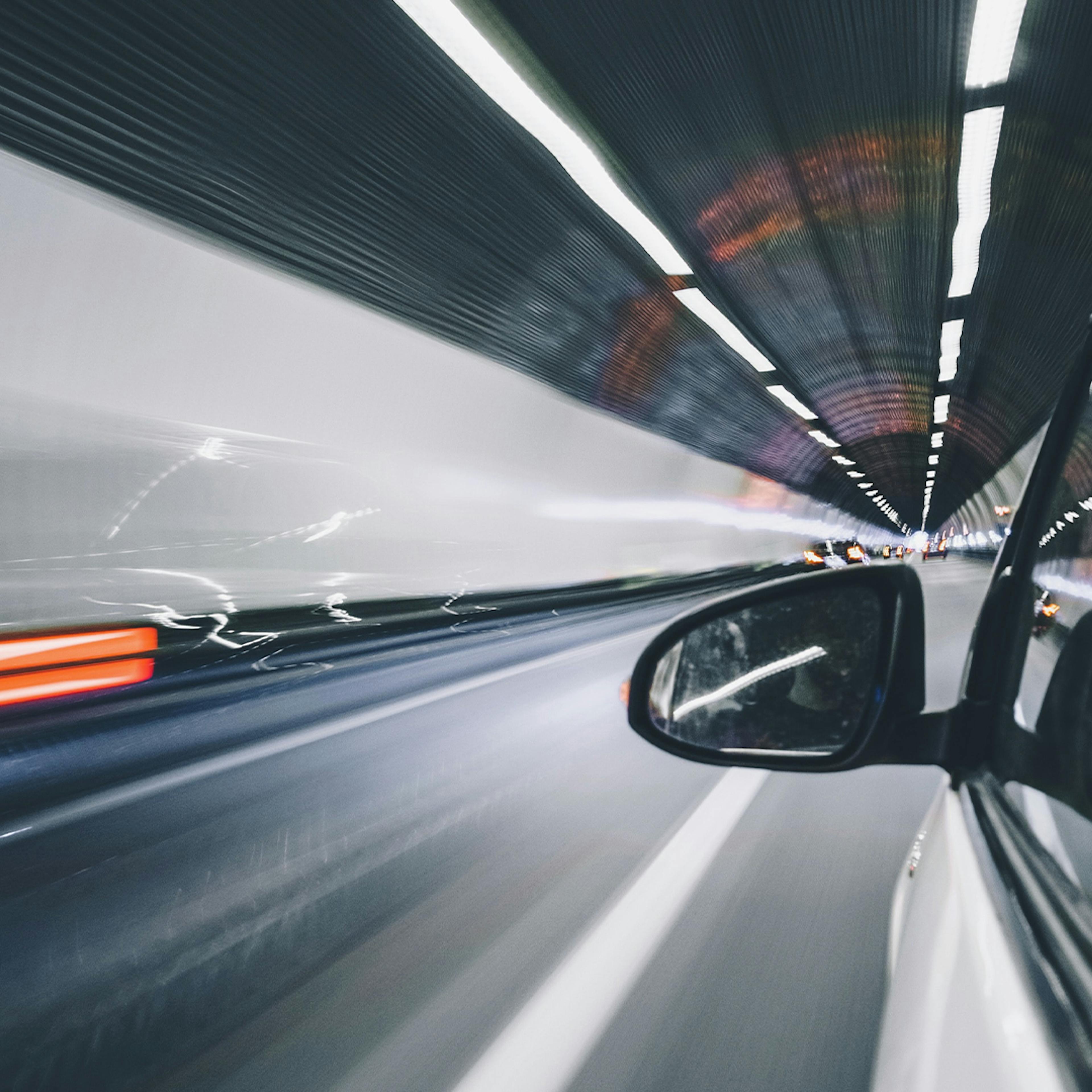 Blick aus dem Fenster eines Autos, das mit hoher Geschwindigkeit durch einen Tunnel fährt.