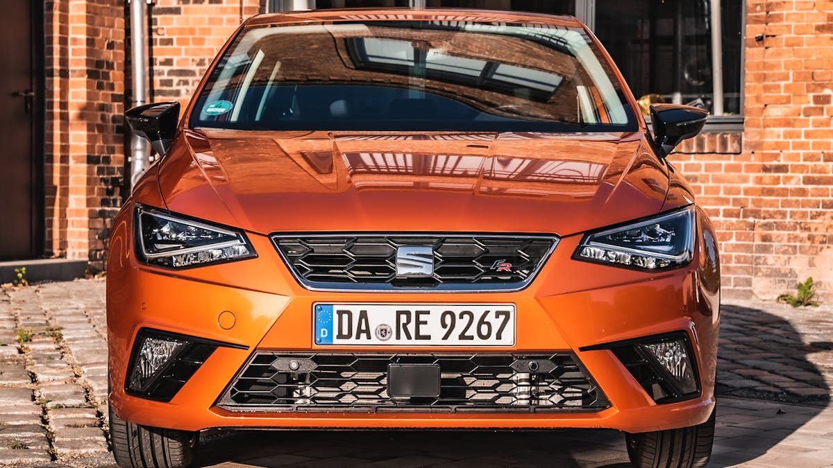Blick auf die Front eines orangefarbenen Seat Ibiza 1.0 TGI, der vor einem Backsteingebäude steht 