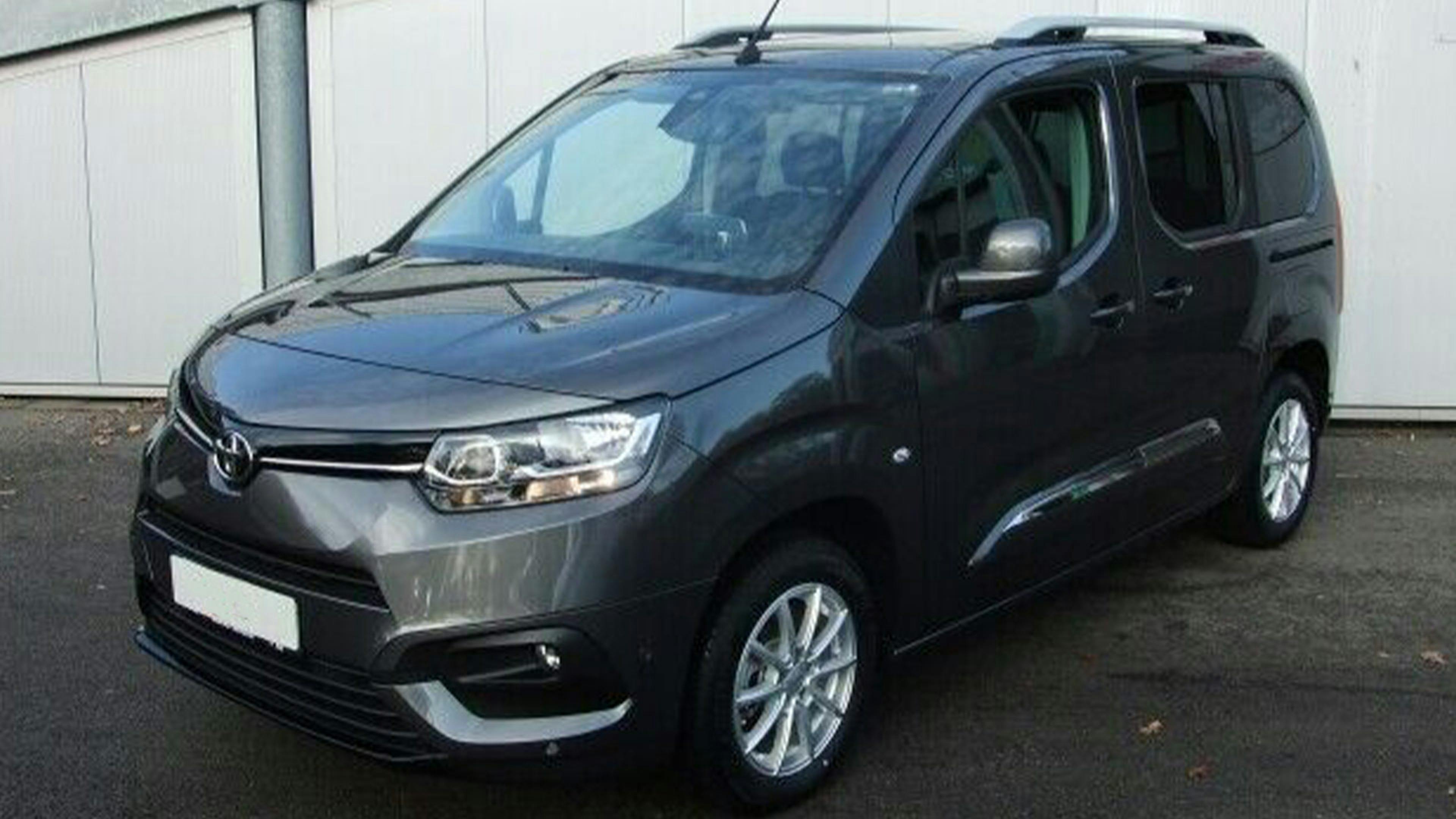 Ein schwarzer Toyota Proace City Verso Hochdachkombi steht vor einem weißen Gebäude.